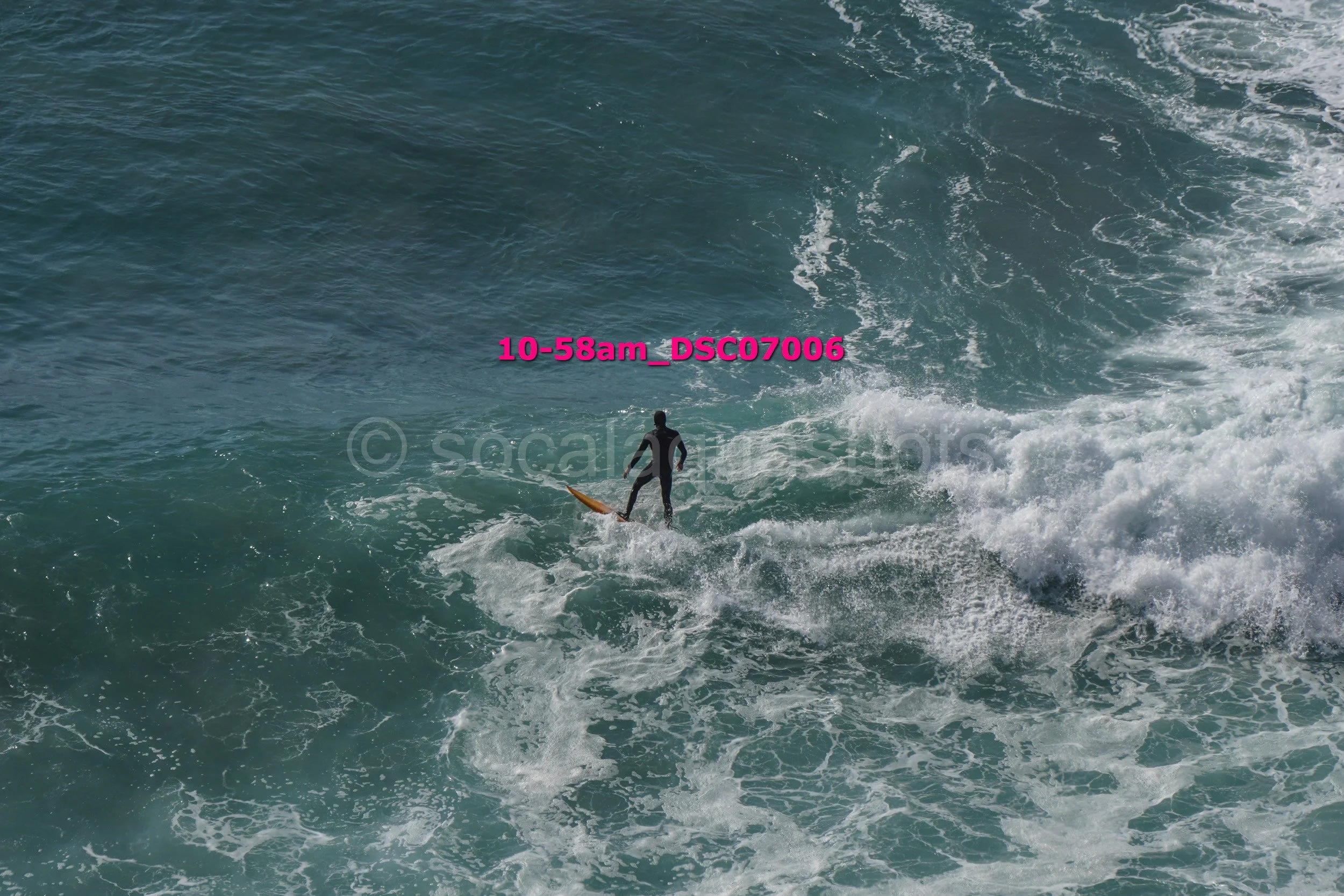 Surfer riding a wave in the ocean on a sunny day.