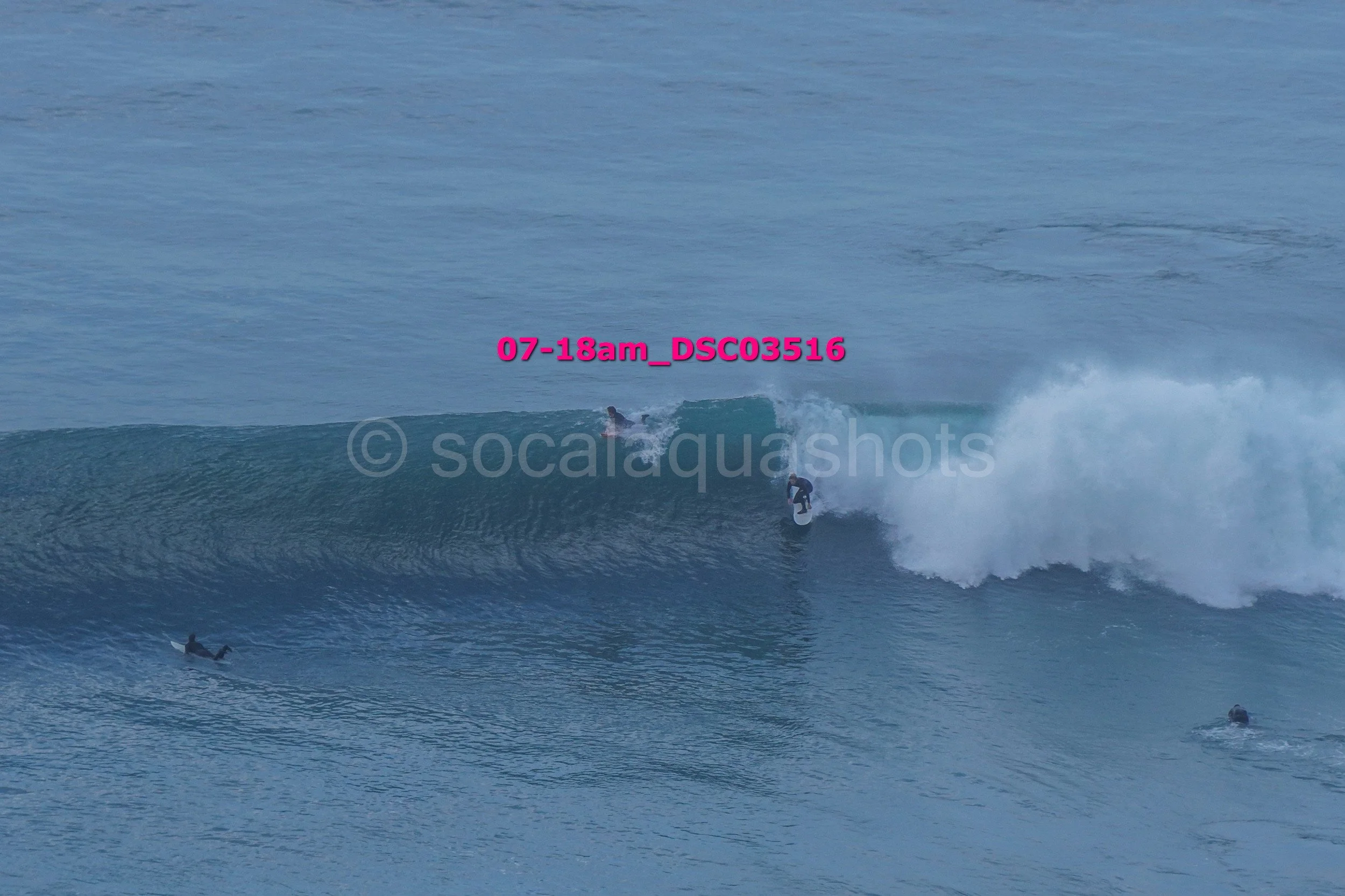 Multiple surfers riding and waiting on ocean waves in the water.