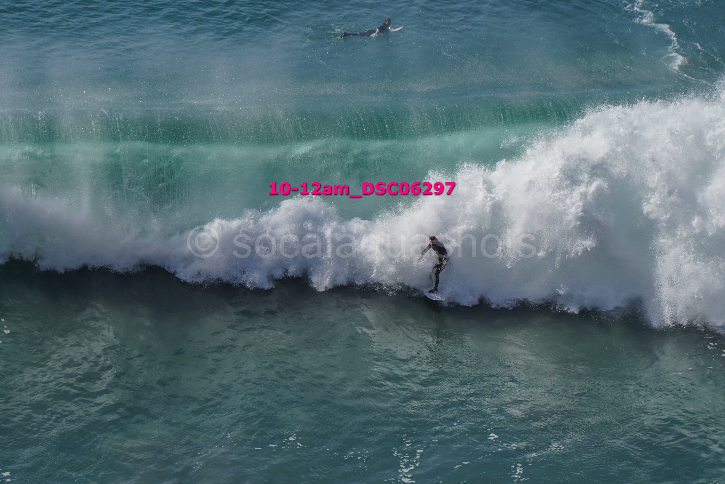 A person surfing on a wave in the ocean with another surfer riding a different wave in the background