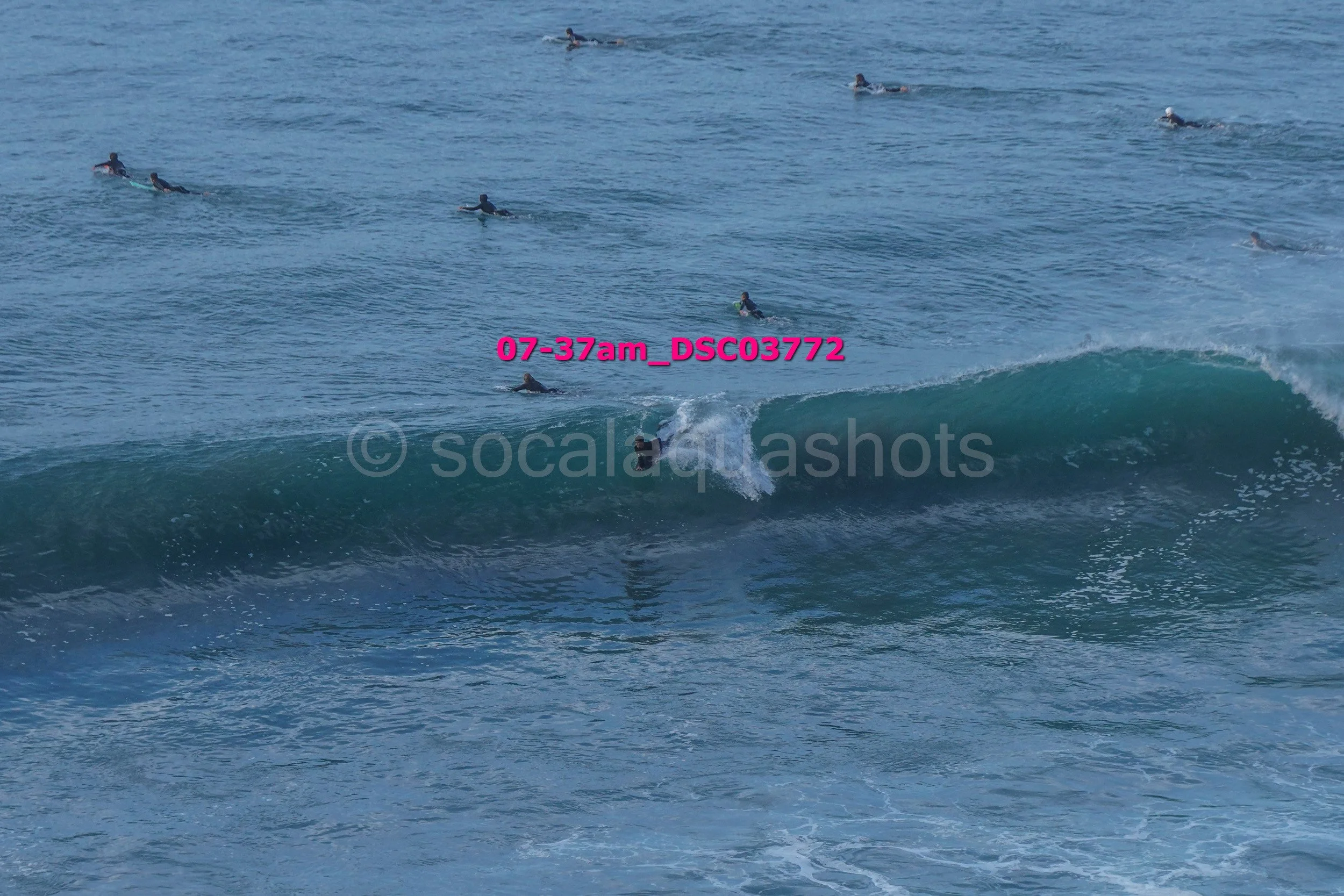 A person surfing on a wave with multiple surfers in the water in the background near the shore.