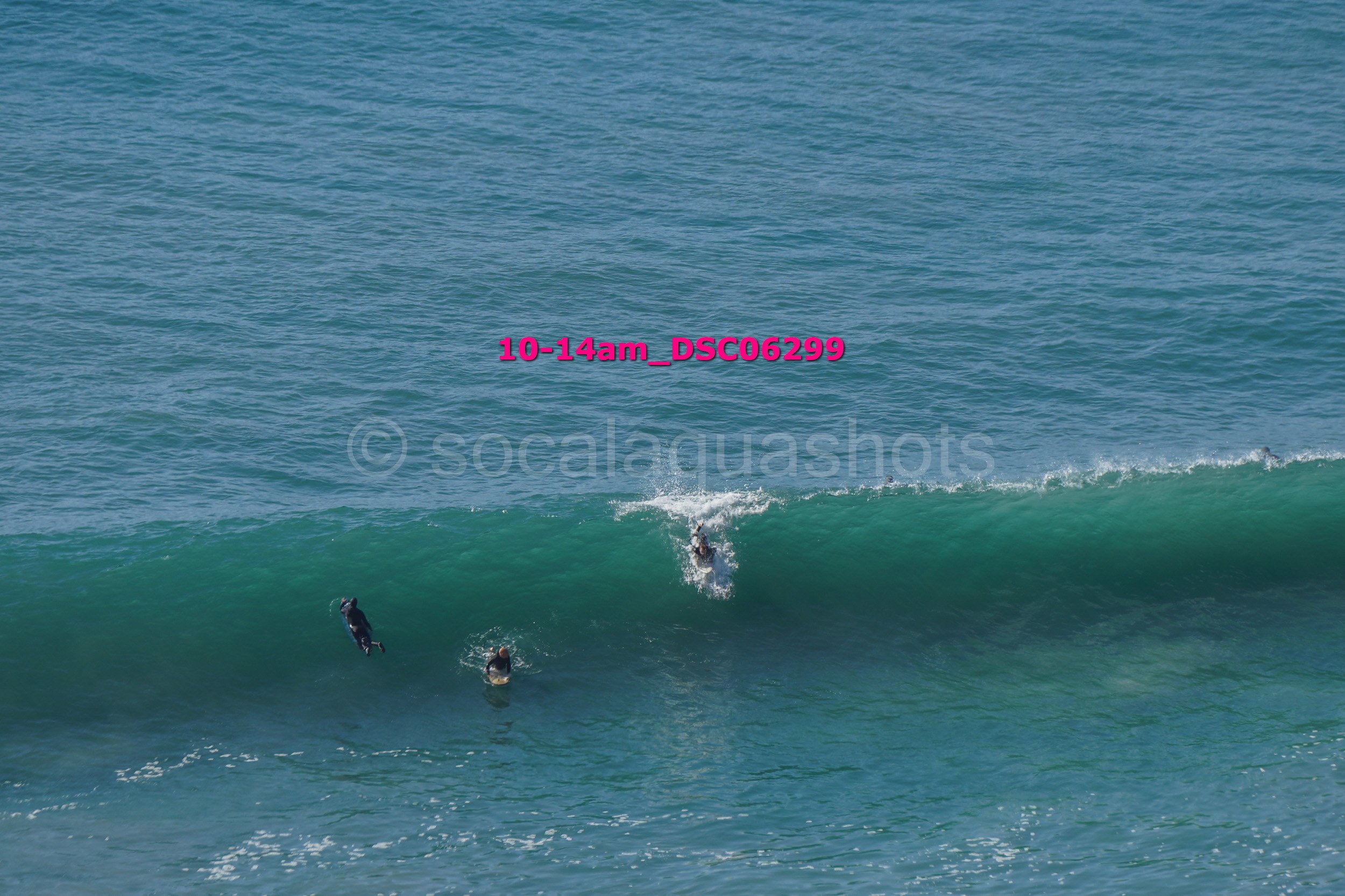 Three surfers riding a wave in the ocean