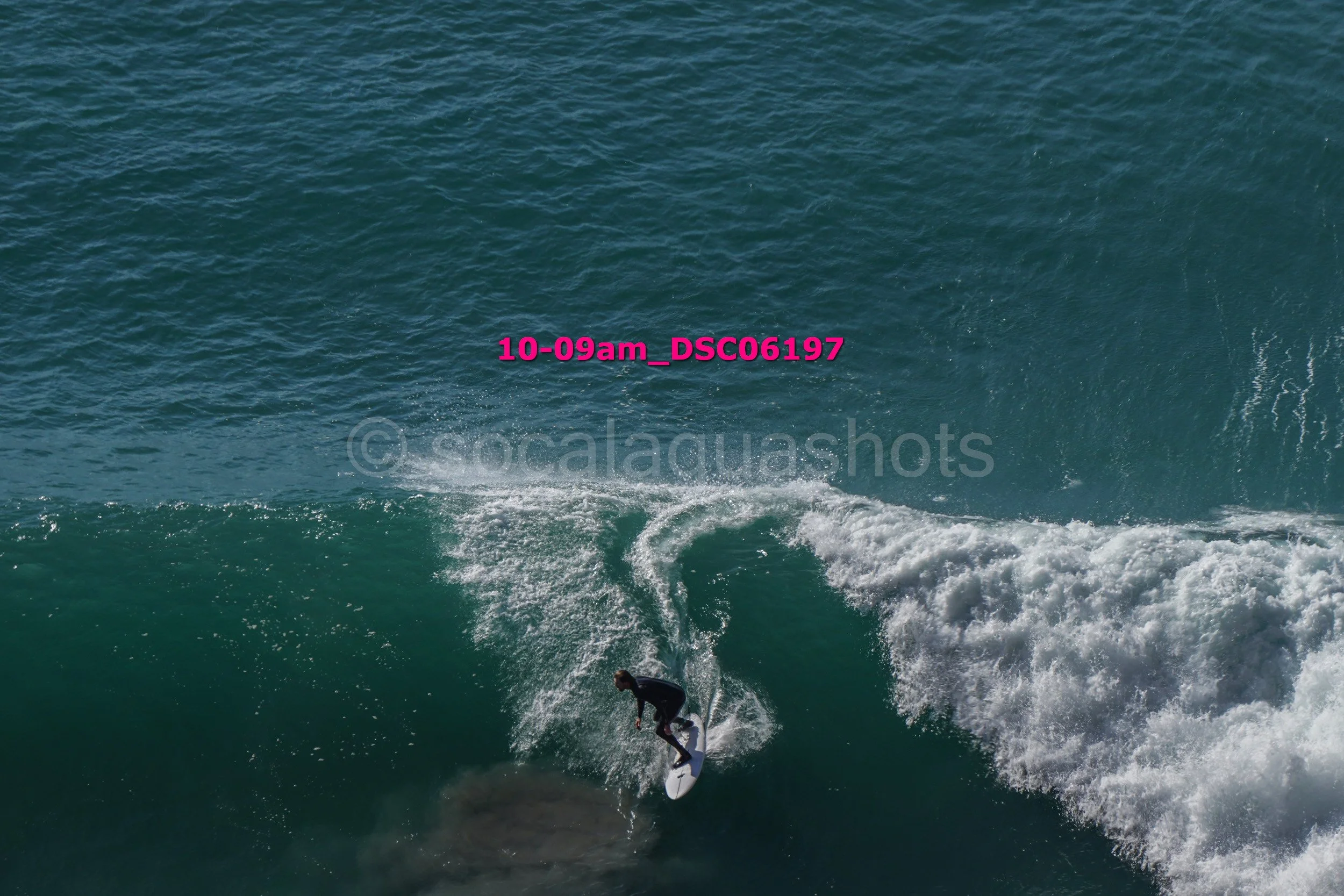 A person surfing on a wave in the ocean with a spray of water behind them.