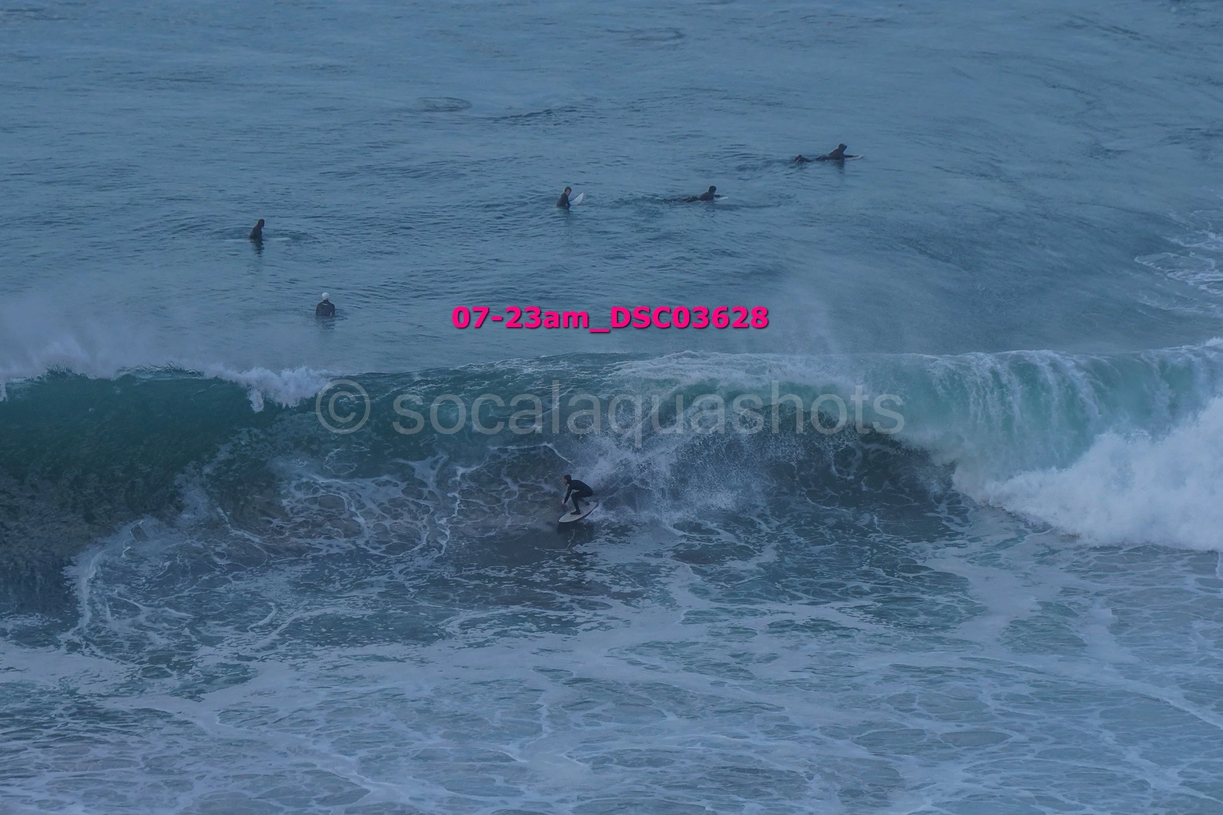 Surfer riding a wave with several surfers in the water in the background.