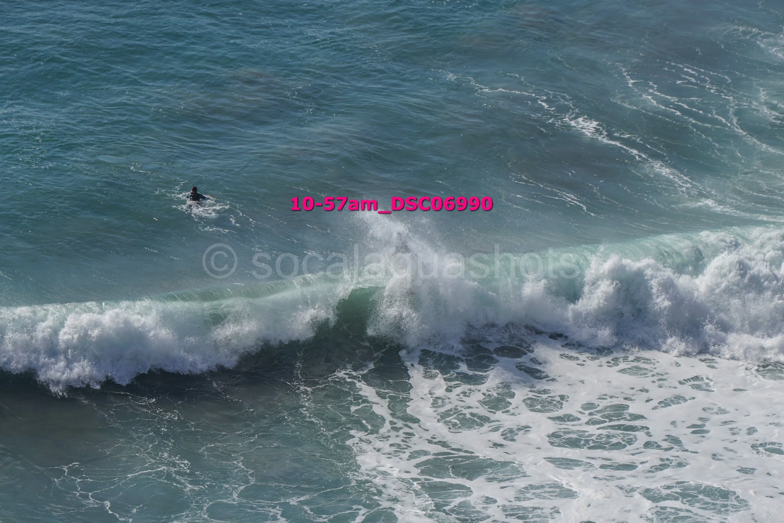 A person surfing in the ocean with breaking waves.