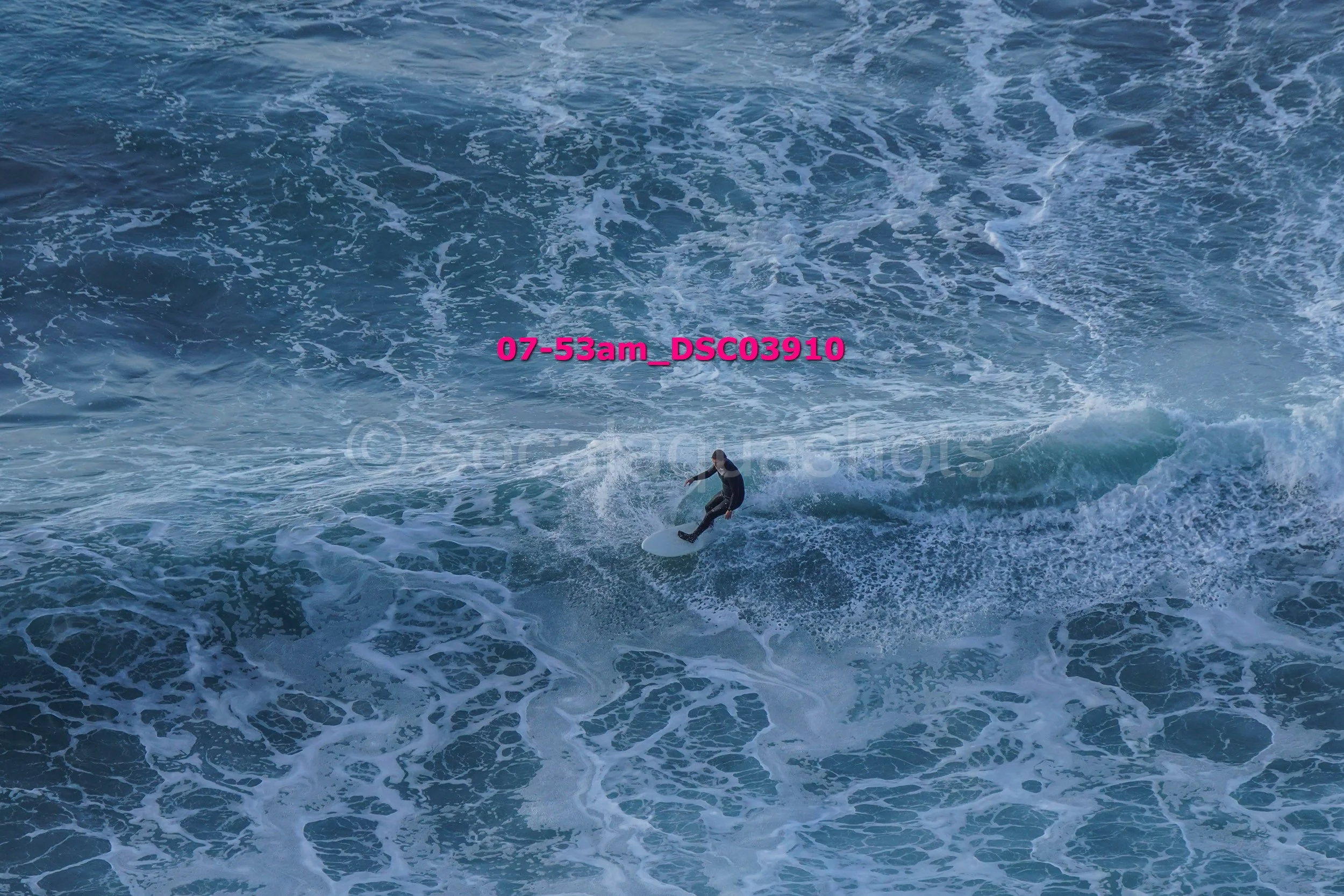 A person surfing on a blue ocean wave.