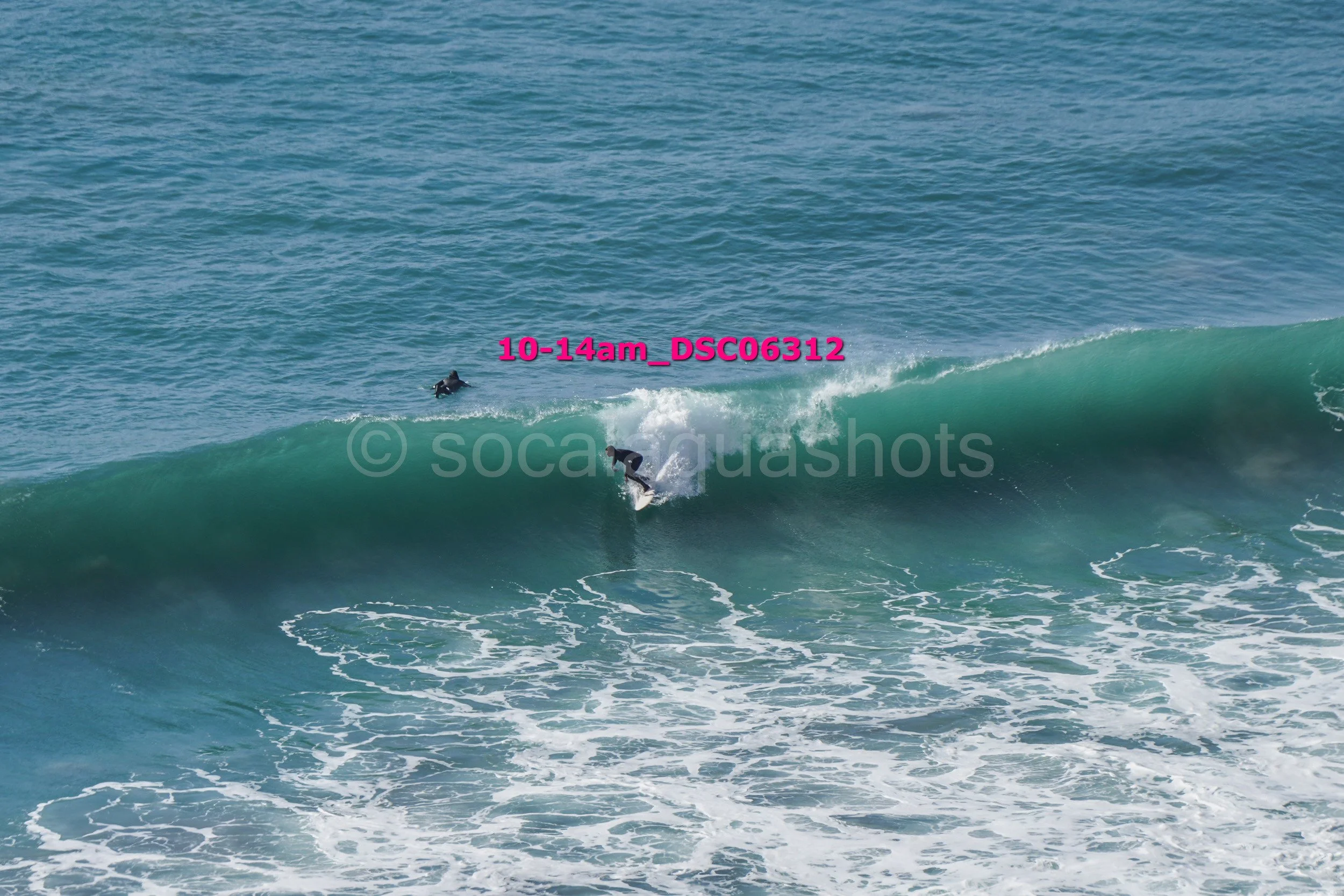 A person surfing on a wave with two other surfers in the water nearby at the beach.