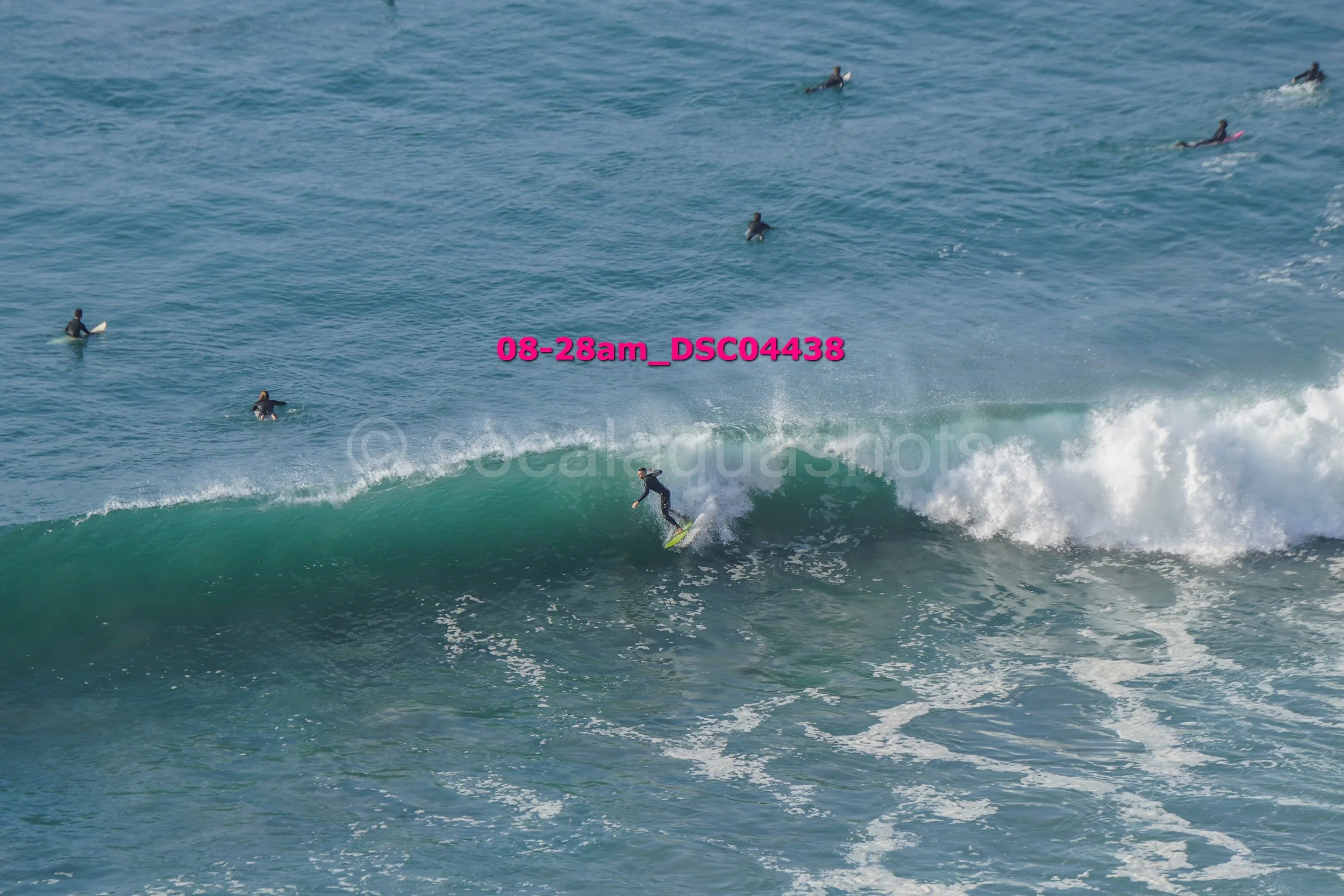 Surfer riding a wave in the ocean with several surfers in the background.