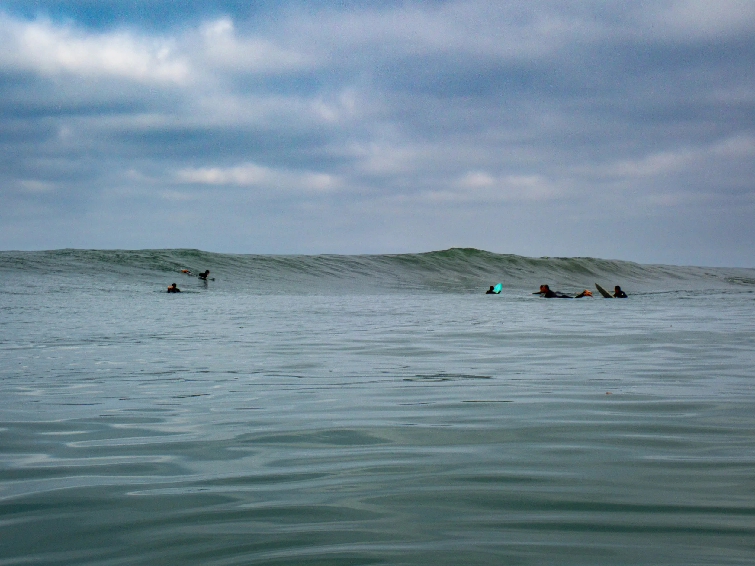 Group of surfers in the ocean waiting for waves on a cloudy day.