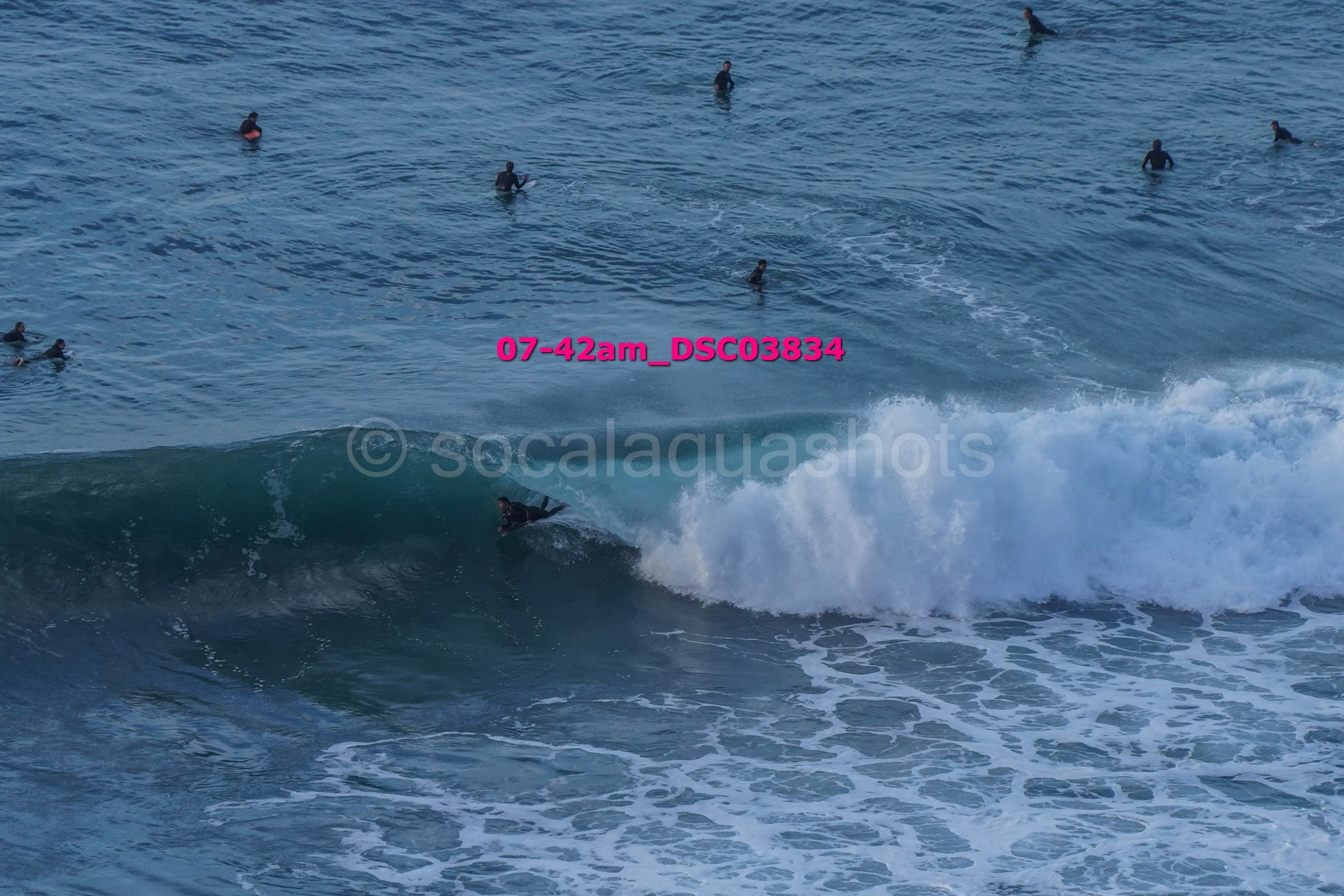 Surfer riding a wave in the ocean with several swimmers in the background