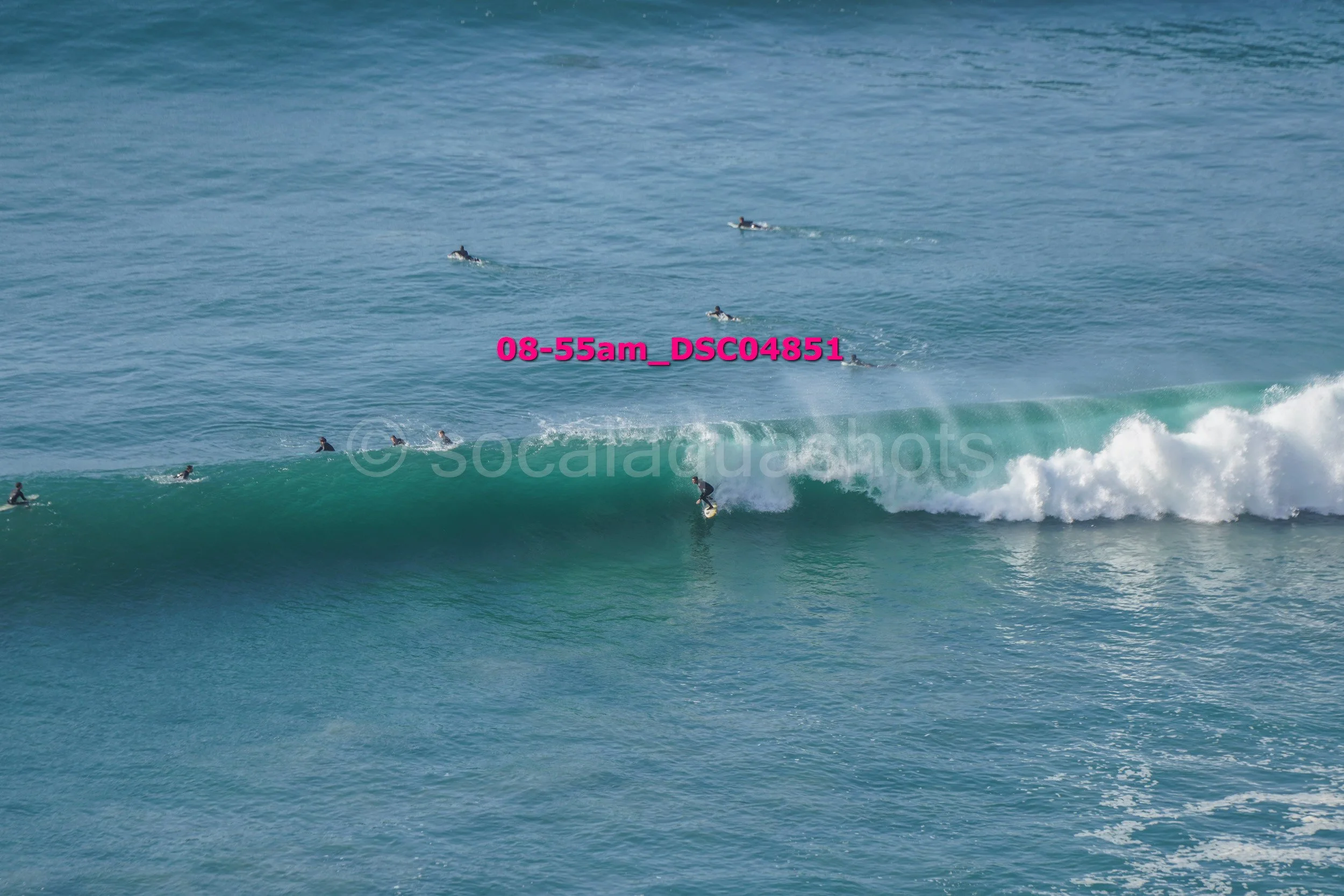 Surfer riding a wave with multiple surfers in the water behind him