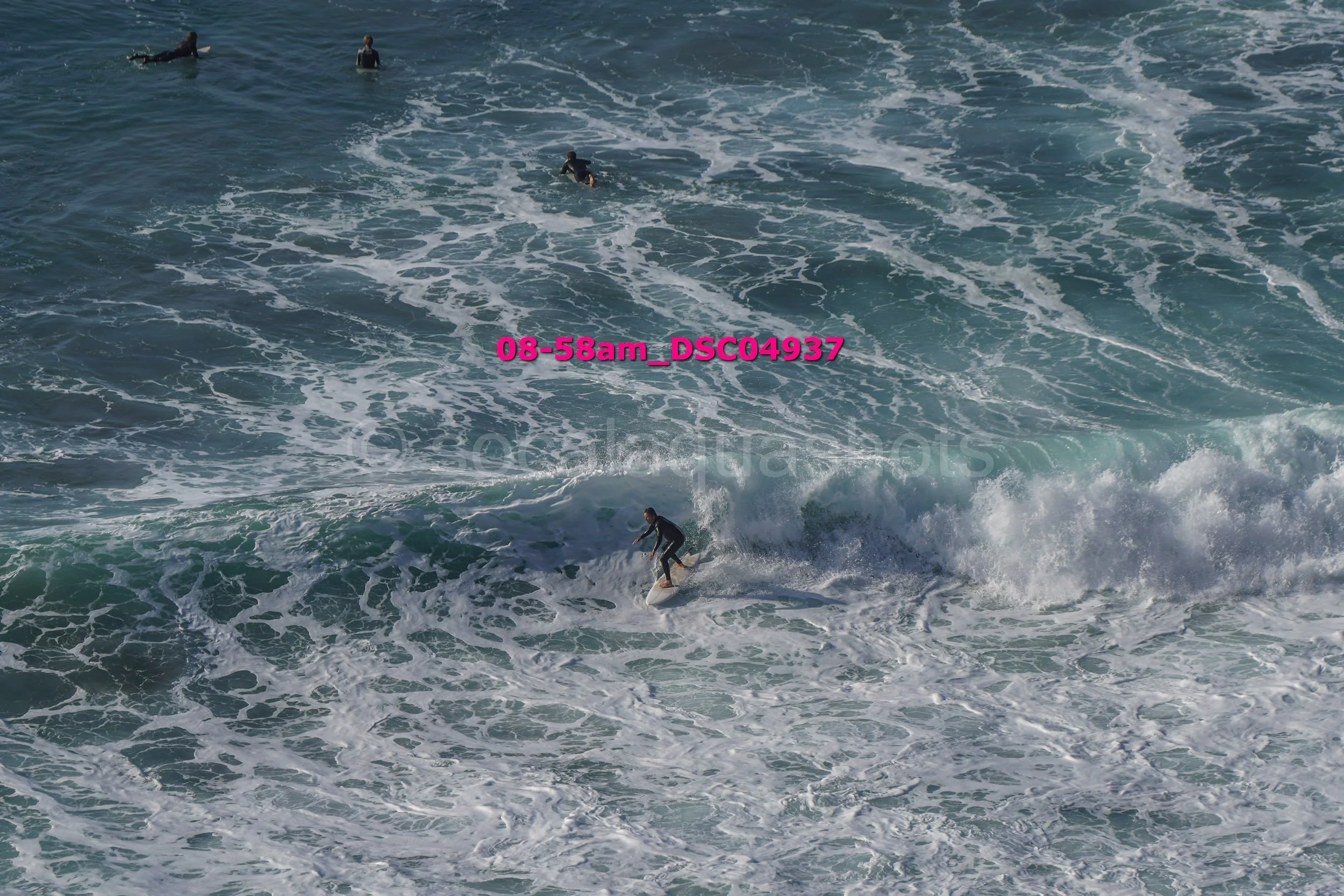A surfer riding a wave with three other surfers in the water nearby.