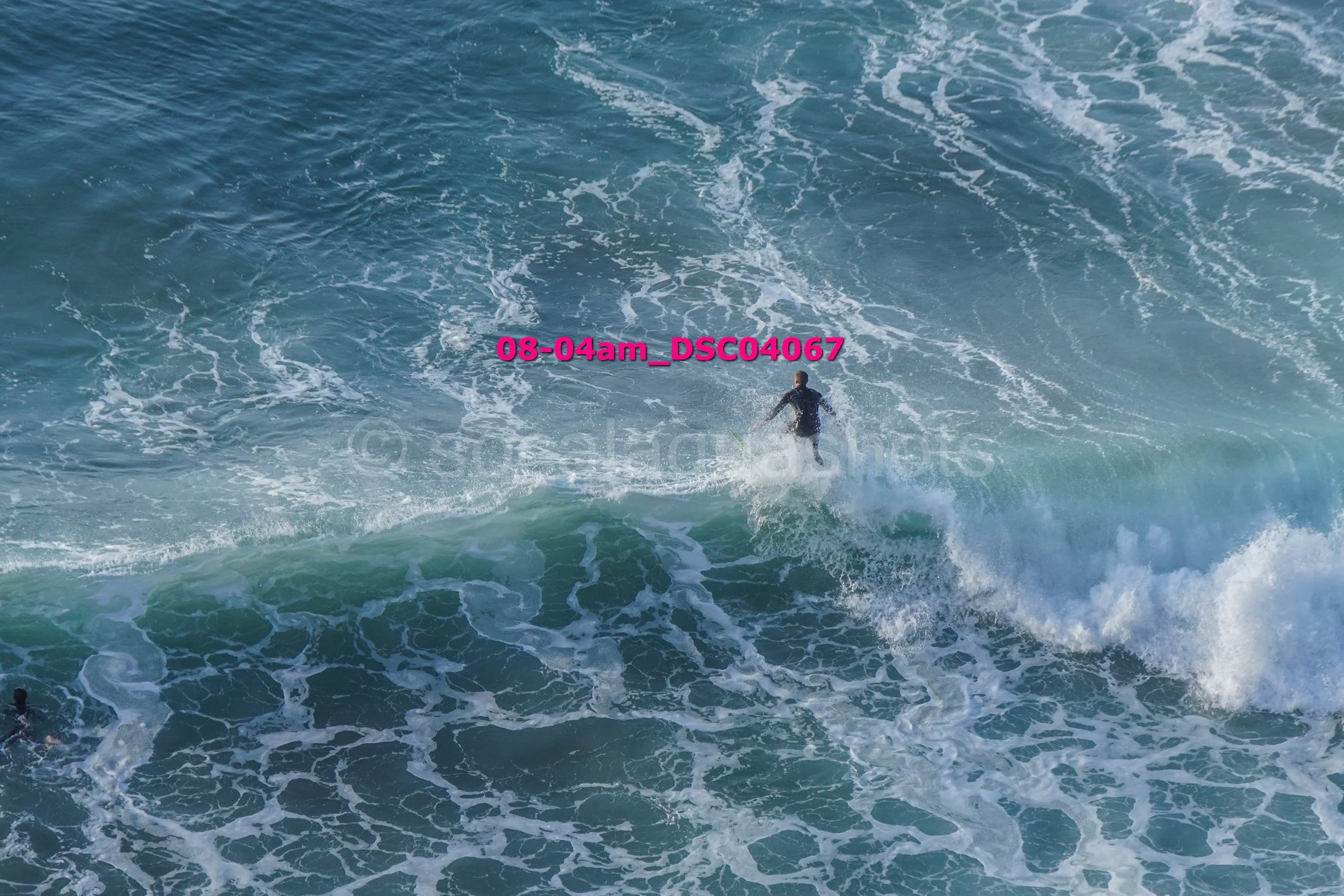 A person surfing on a large wave in the ocean.