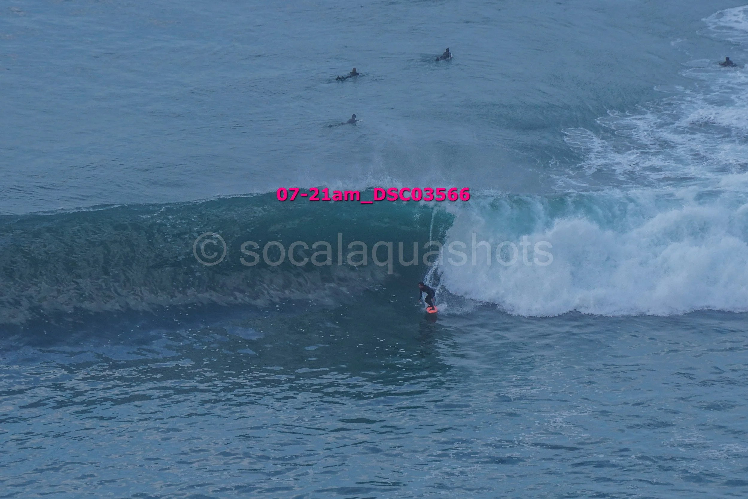 Surfer riding a large wave with several surfers in the distance in the ocean