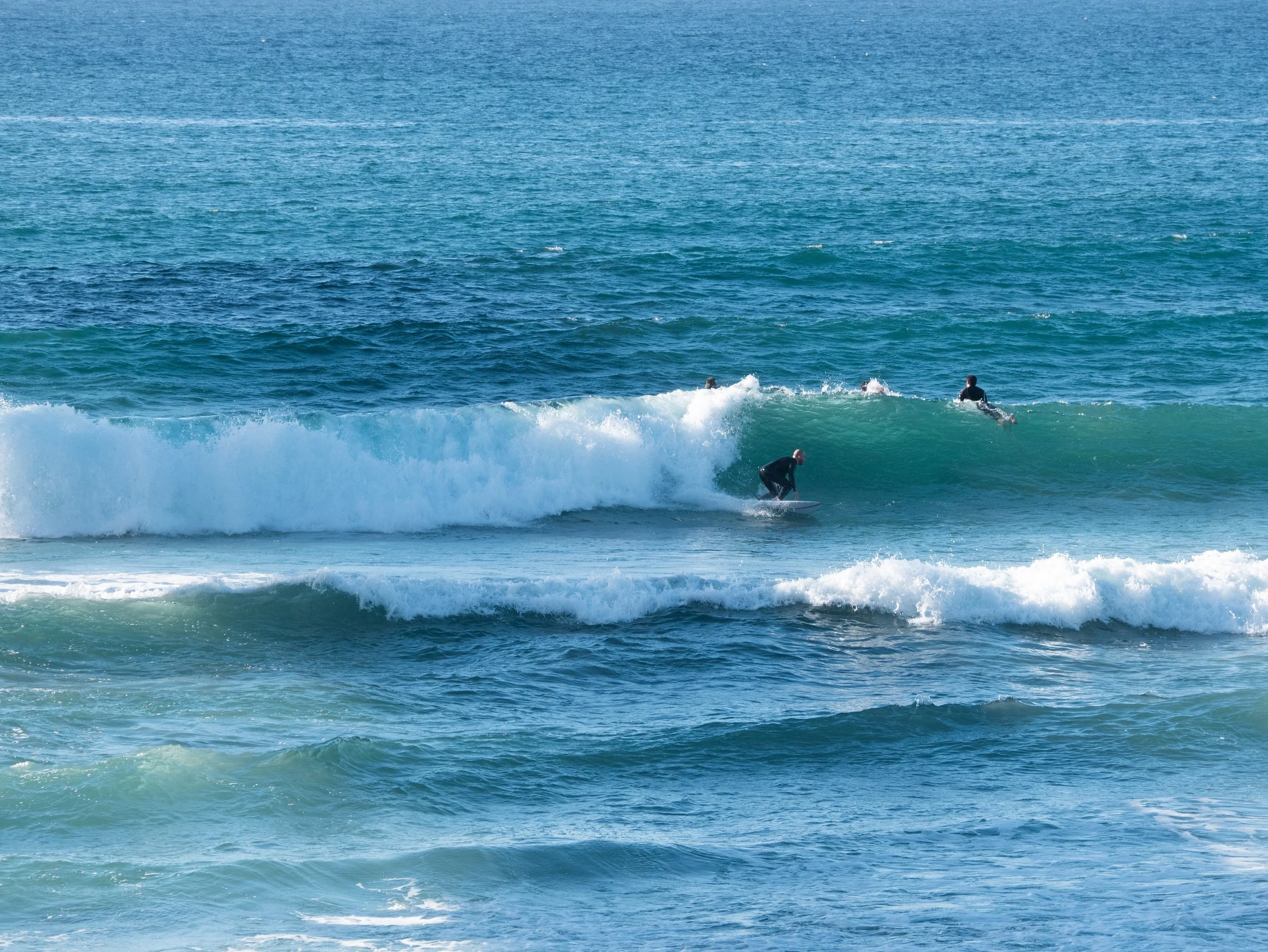 Group of surfers riding and waiting on ocean waves at the beach.
