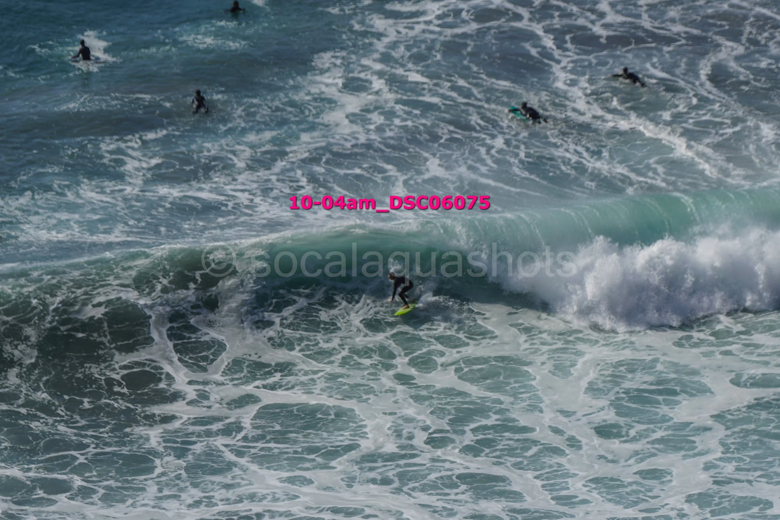 A surfer riding a wave with several other surfers in the water nearby in the ocean.