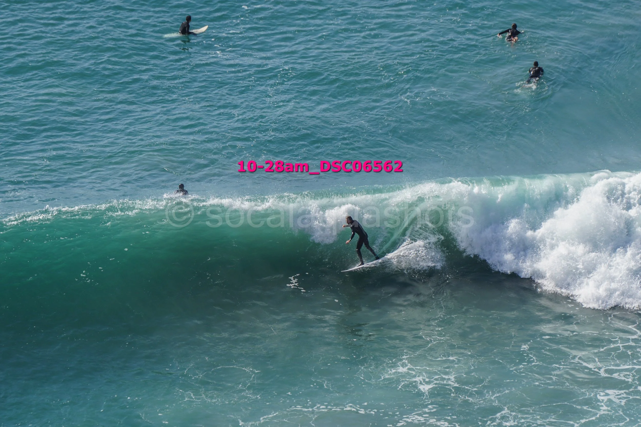 Surfer riding a wave with several people in the water behind him.