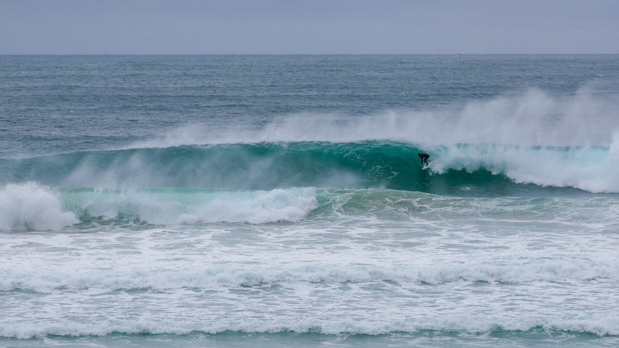 Surfer riding a large wave in the ocean.