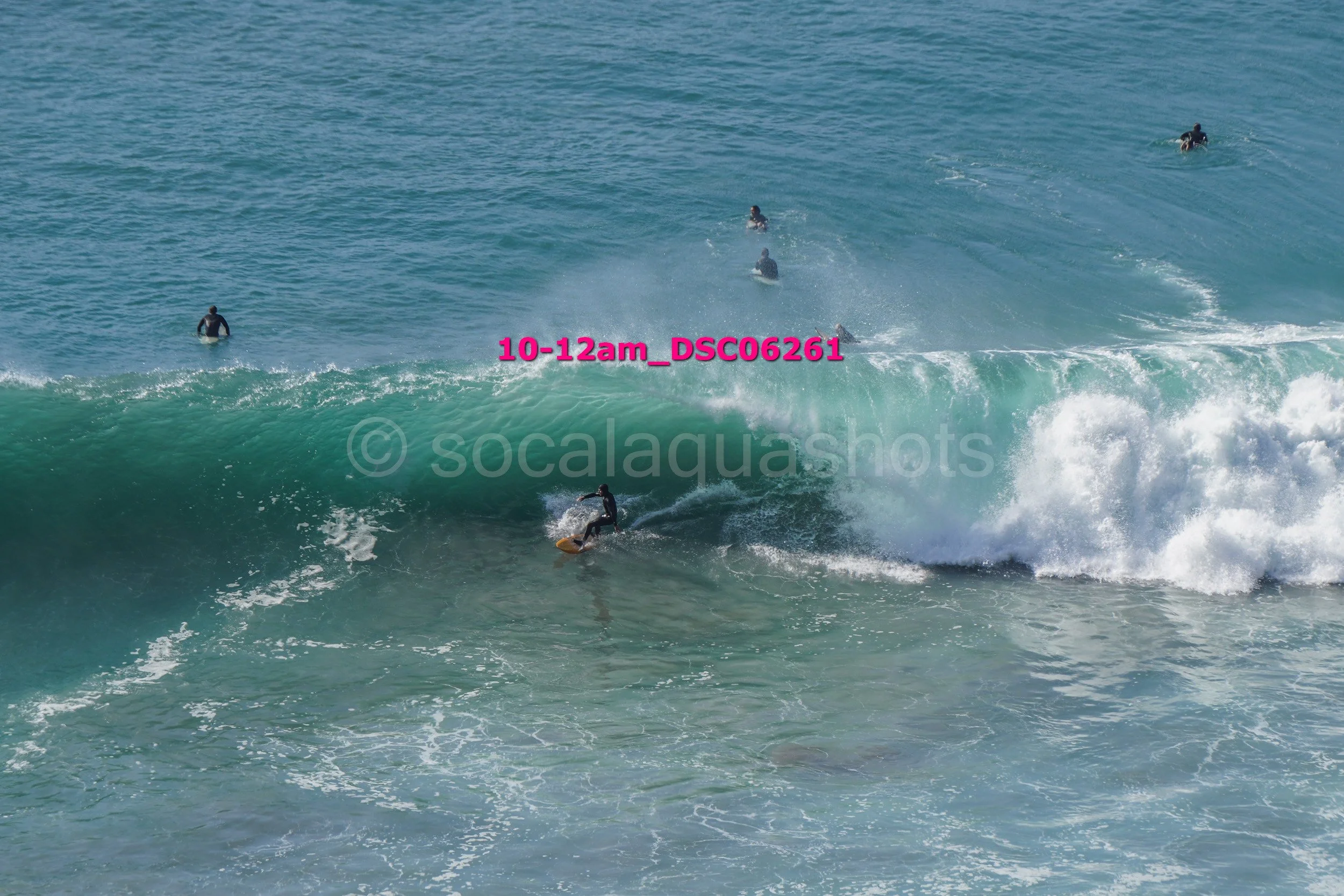 Surfer riding a wave with several people in the water in the background