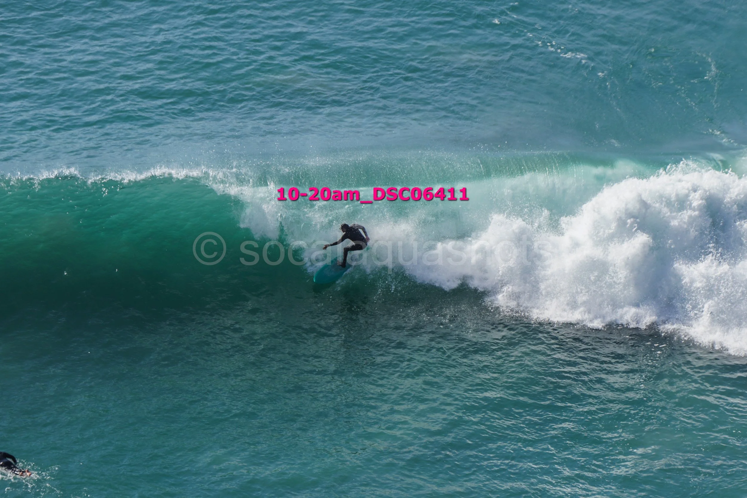 Surfer riding a wave in the ocean with blue-green water.