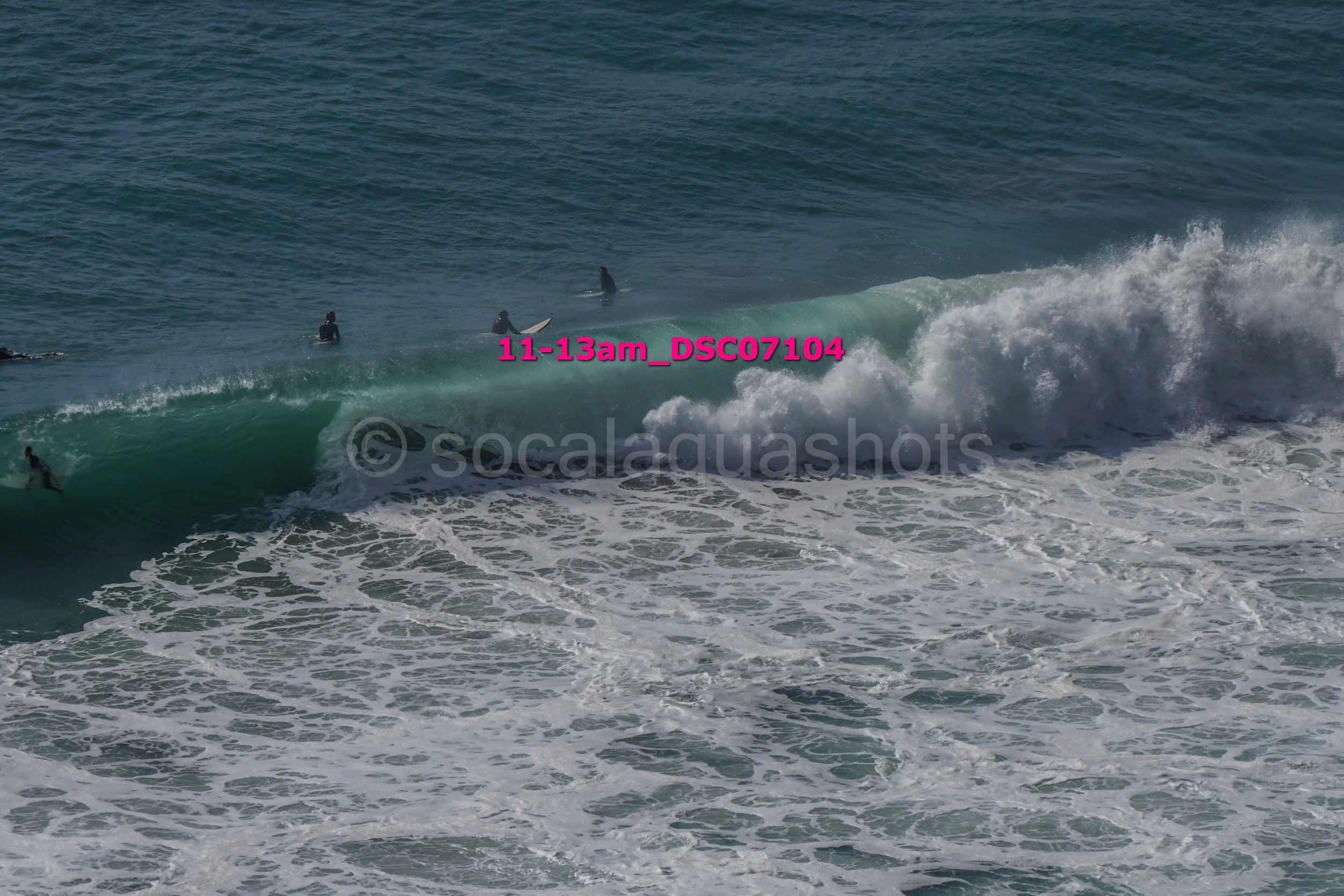 Surfing at the beach with surfers riding a wave and others waiting in the water.