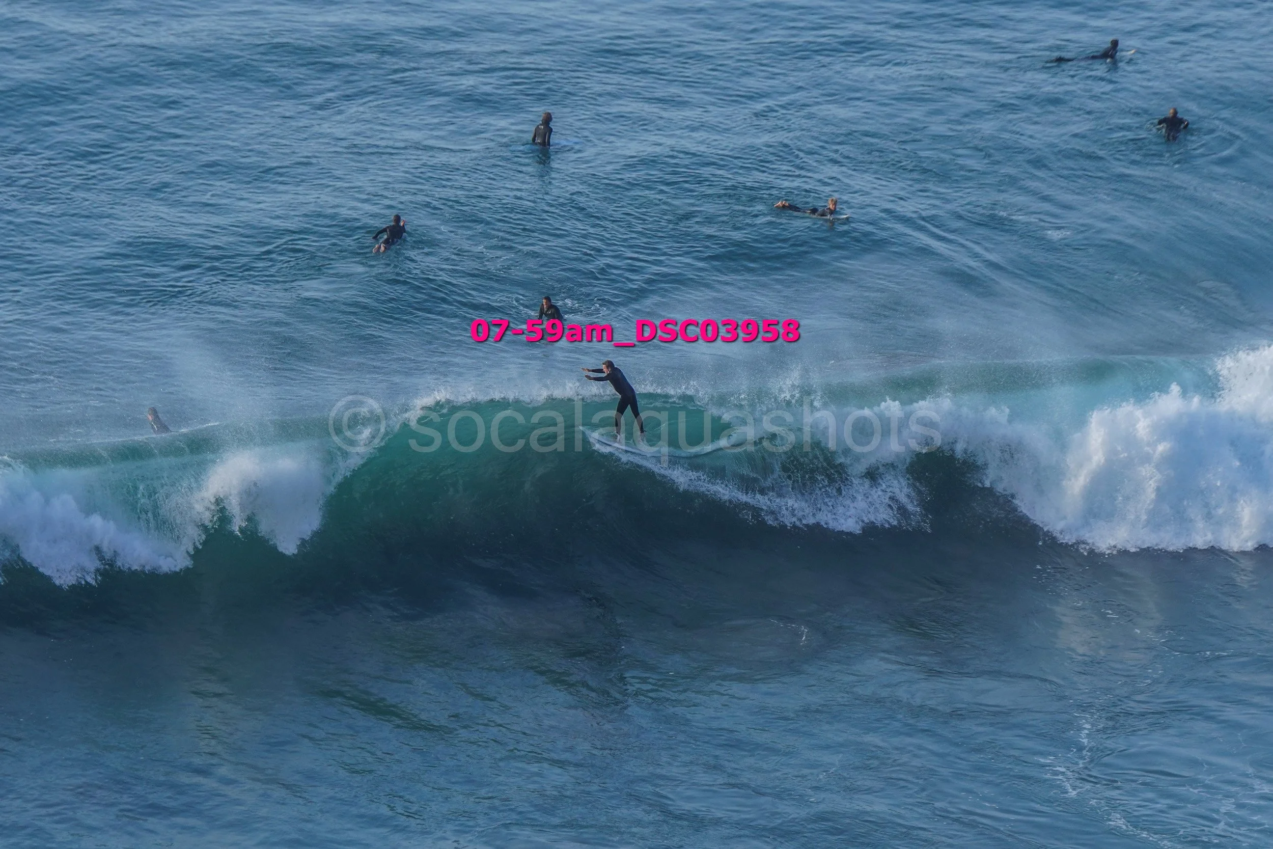 A surfer riding a wave with several surfers in the water in the background.