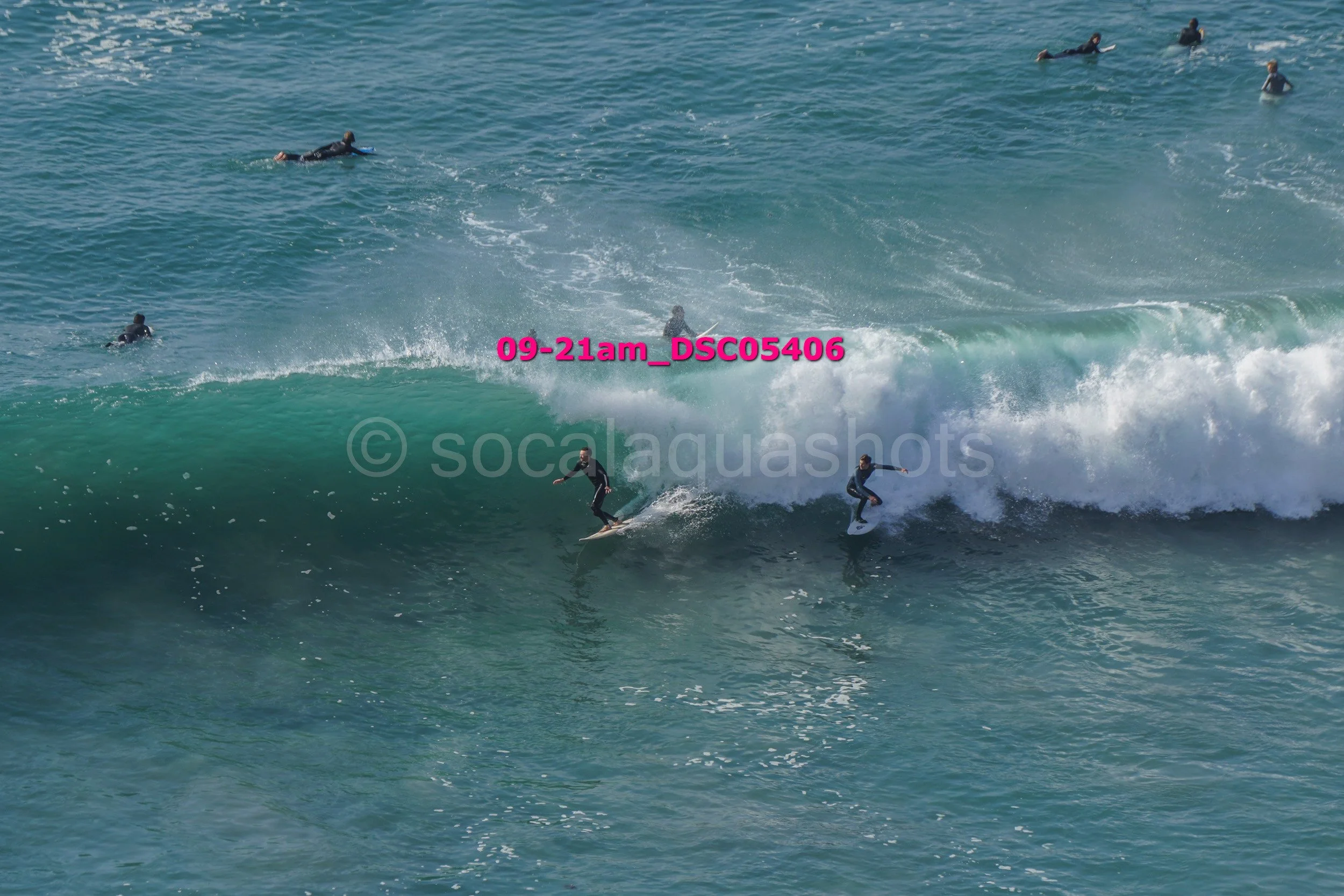 People surfing on large ocean waves with some swimming in the background.