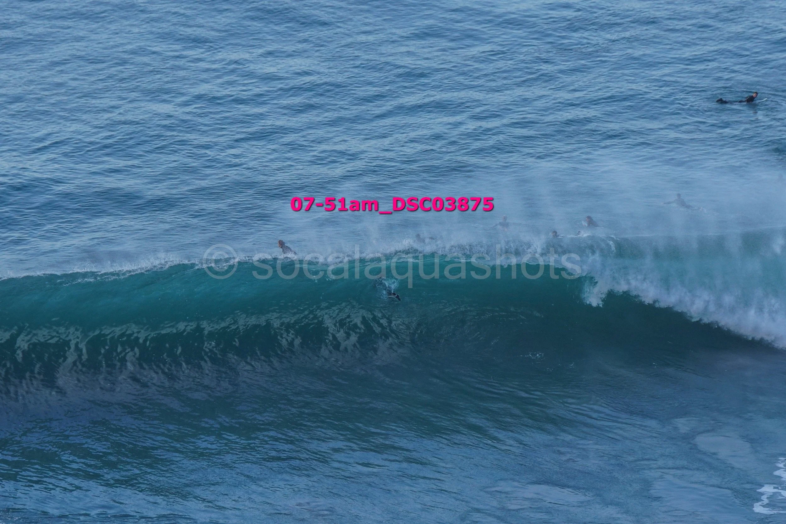 Surfers riding a large wave in the ocean.