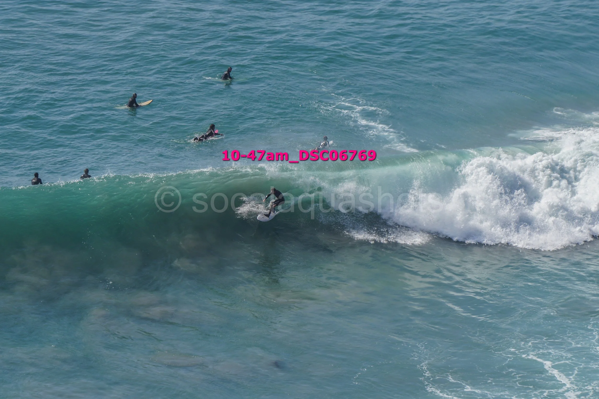 Surfer riding a wave with several surfers in the water around him.