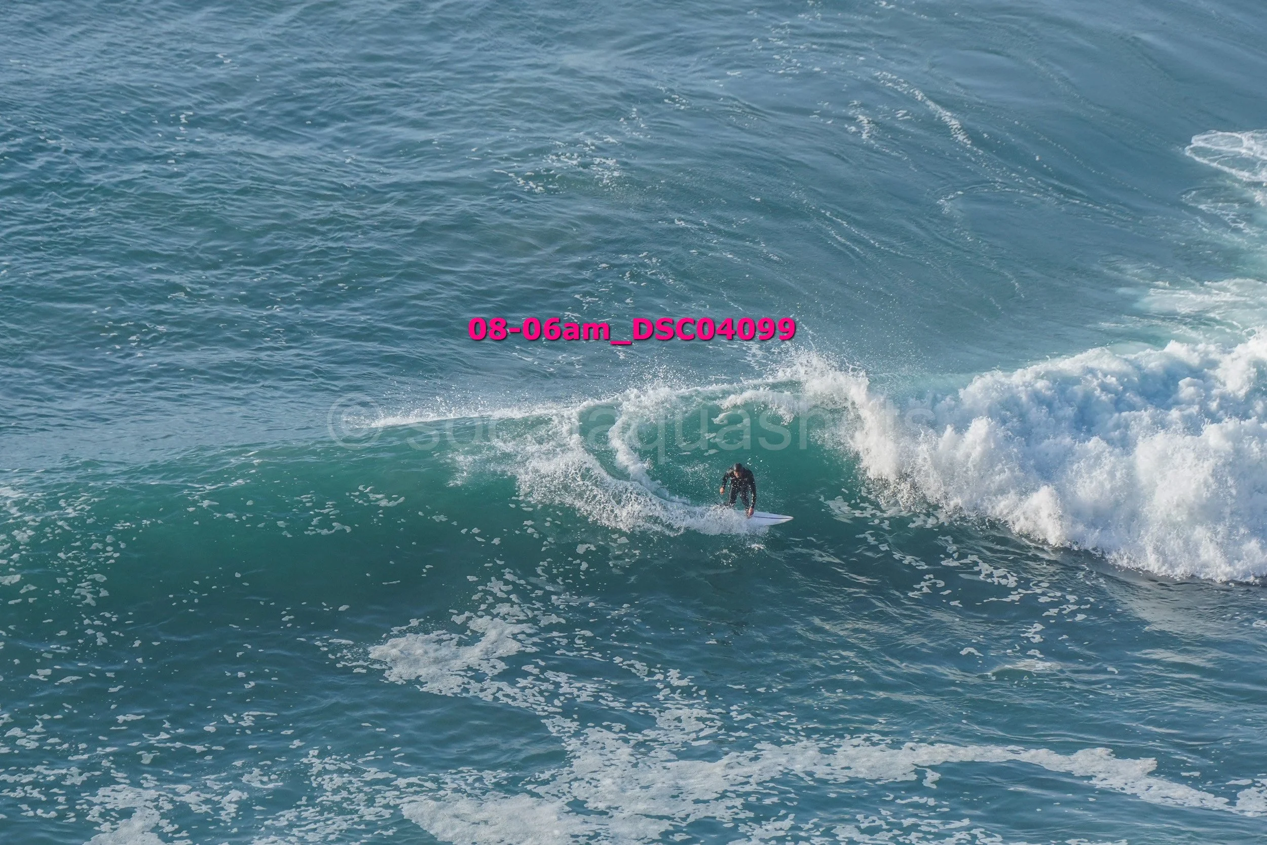 A person surfing on a wave in the ocean, with a timestamp overlay reading '08-06am_DSCO499'.