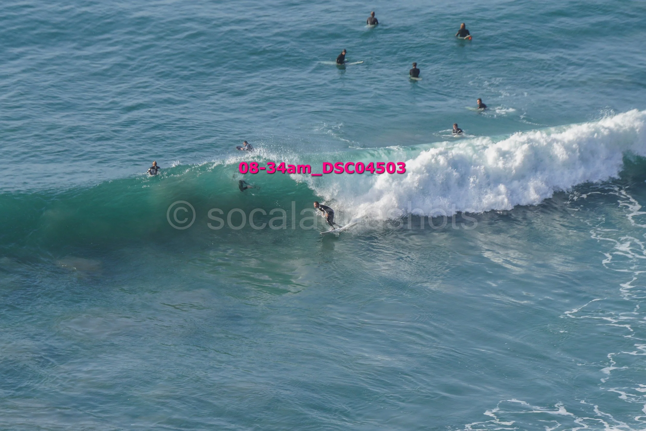 A surfer riding a wave with multiple surfers in the water in the background.