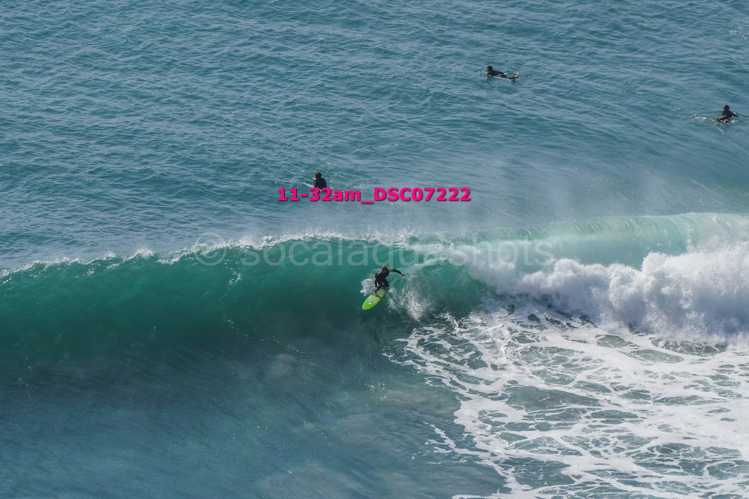 A surfer riding a wave while three other surfers are in the water in the background.