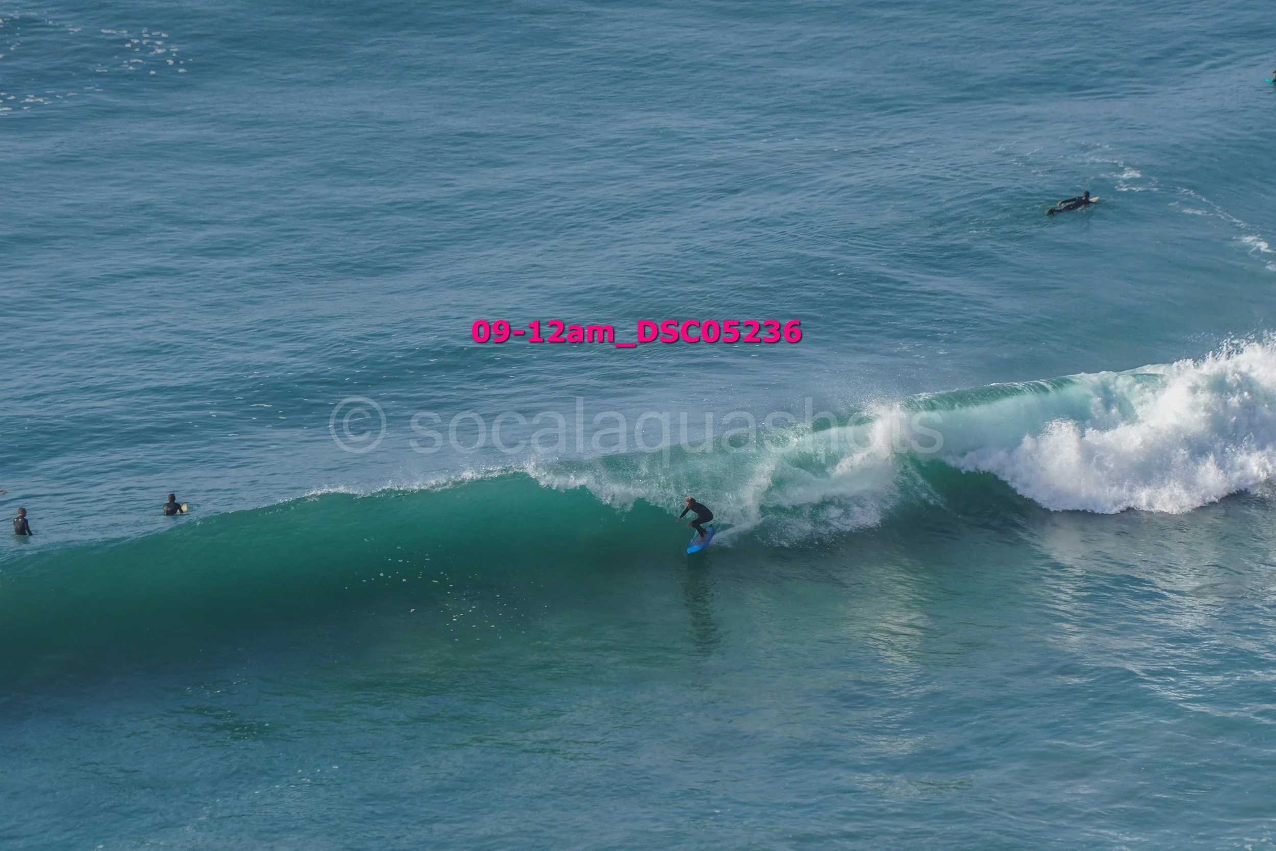 Surfer riding a wave in the ocean with three other people in the water nearby