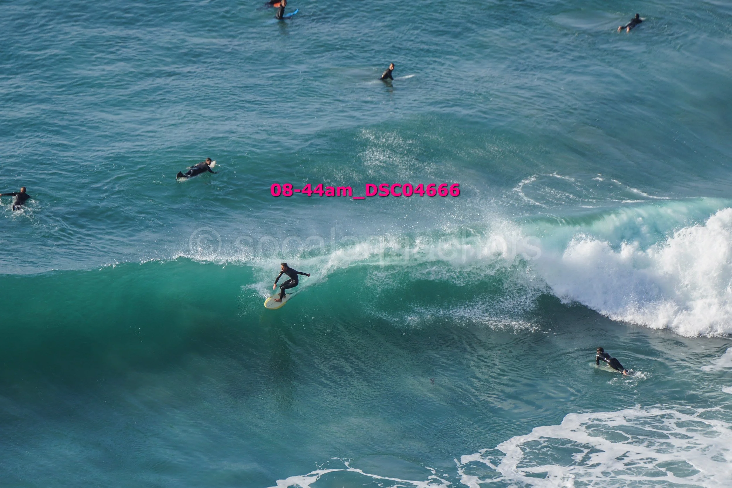 A surfer riding a wave with several other surfers in the water nearby in the ocean.