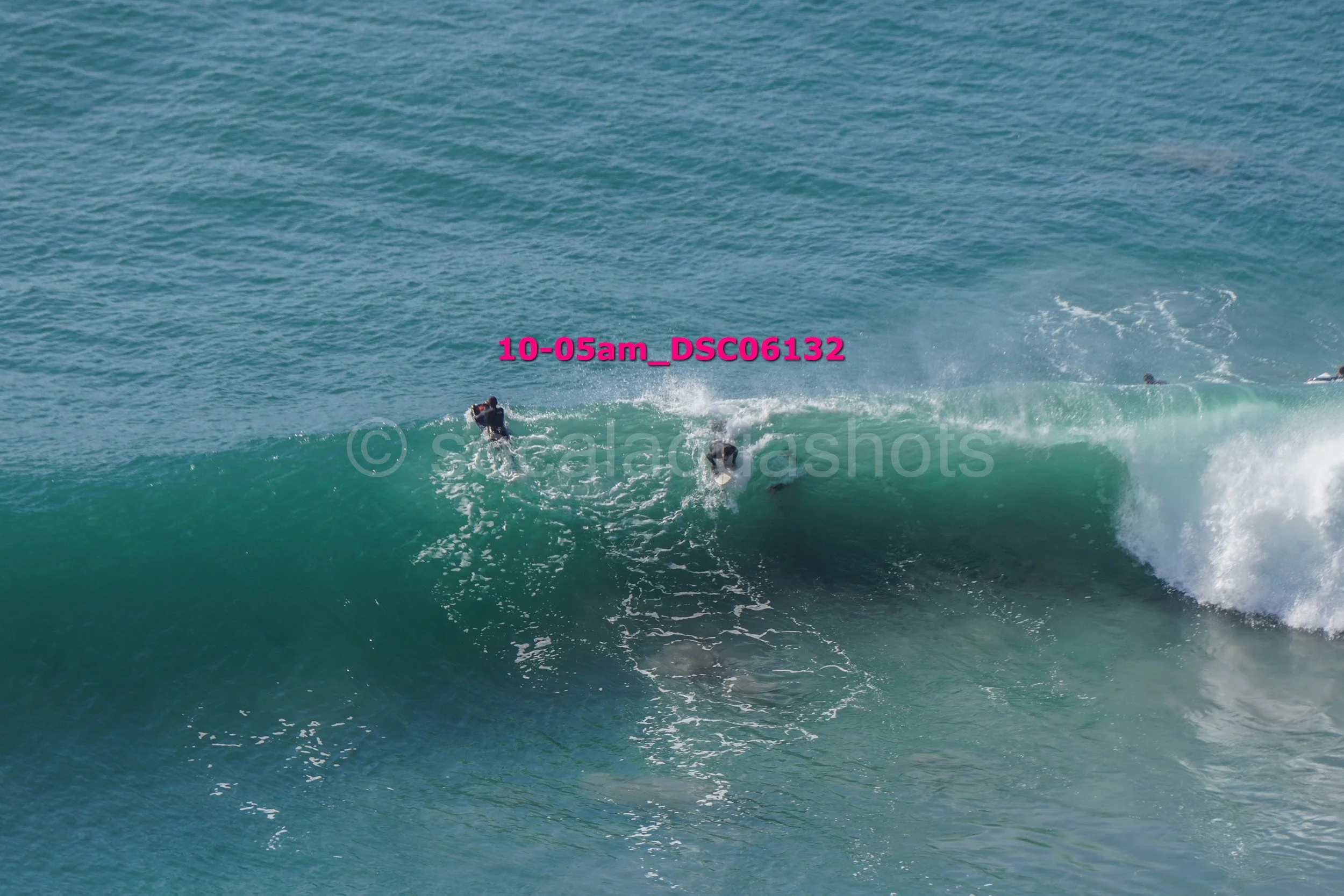 People surfing on a large wave in the ocean.