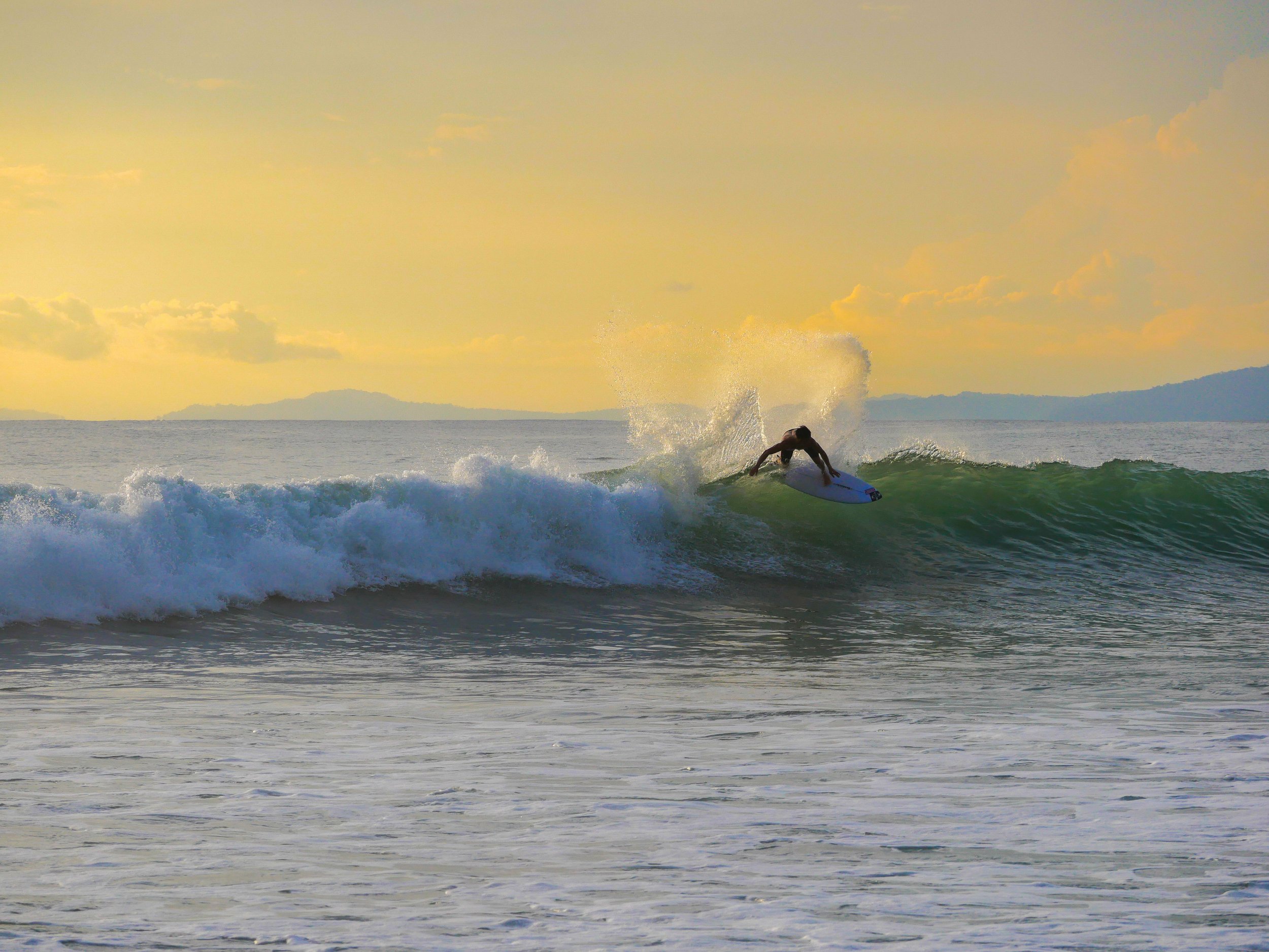 Surfer riding a wave at sunset