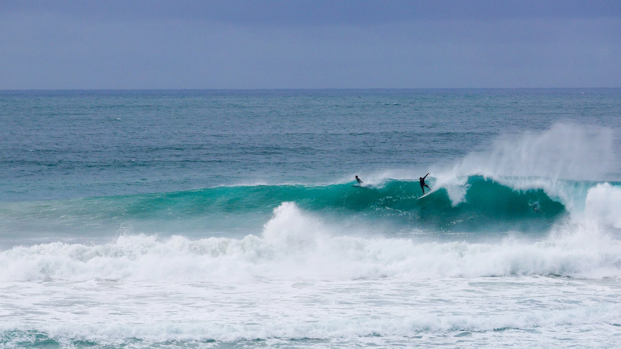 Surfers riding waves on a stormy ocean day