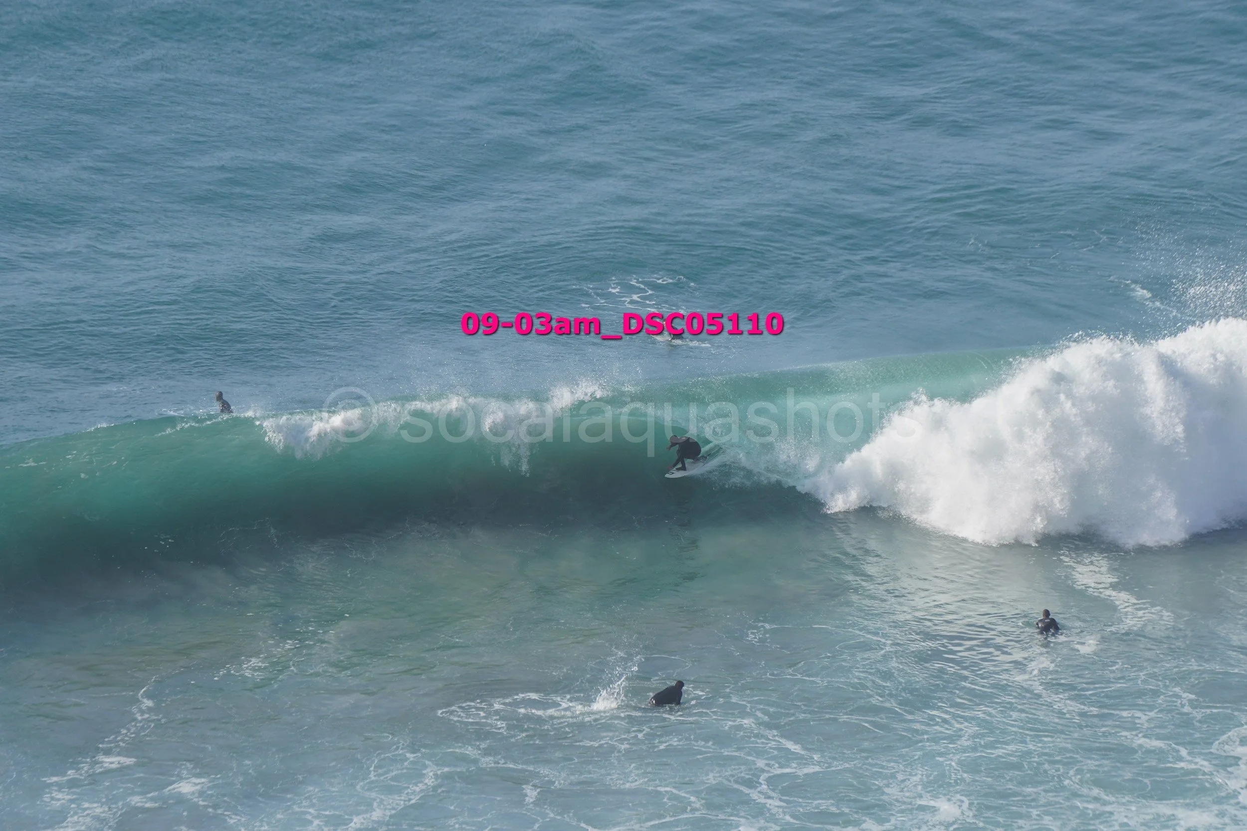 Surfer riding a large wave with other surfers in the water