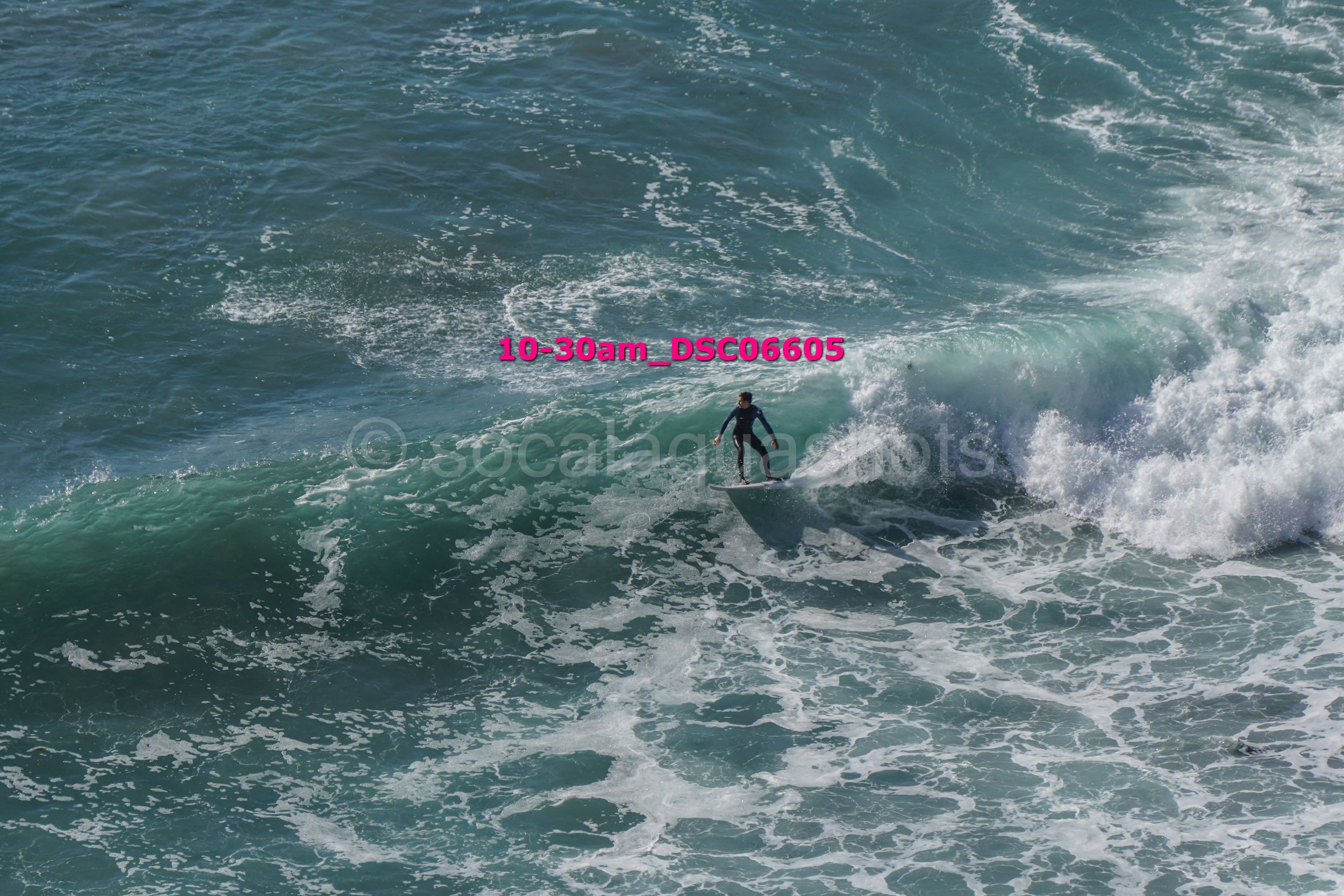 A person surfing on a large wave in the ocean.