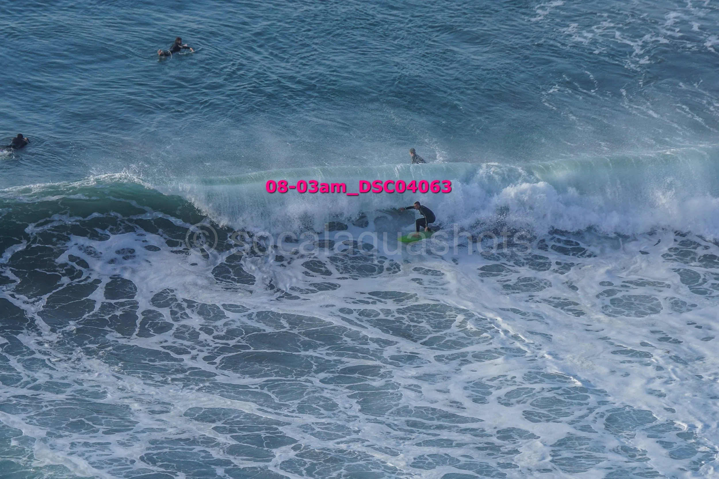 Surfers riding ocean waves with one surfer in the foreground actively on a surfboard.