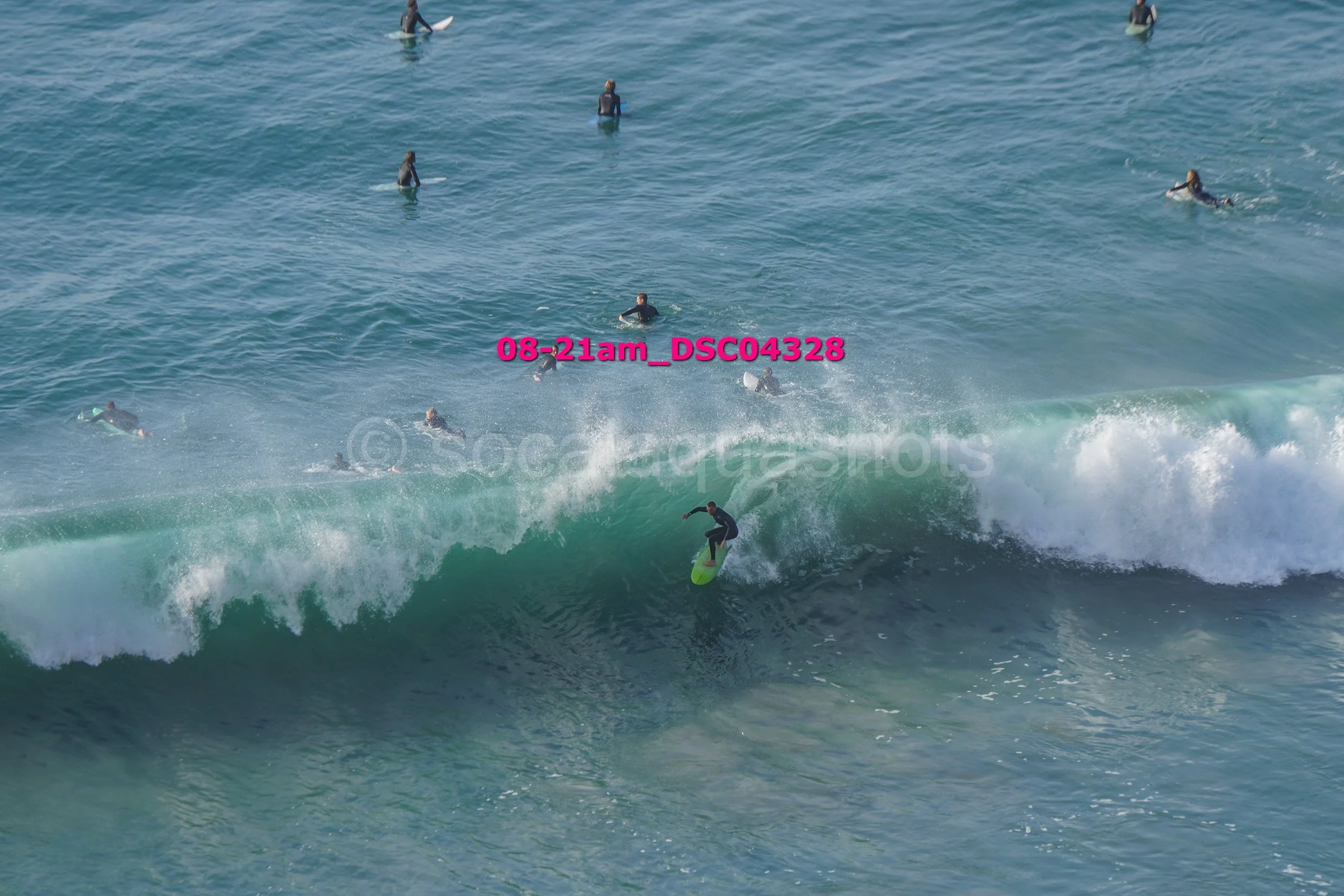A person surfing on a wave with multiple surfers in the water in the background.