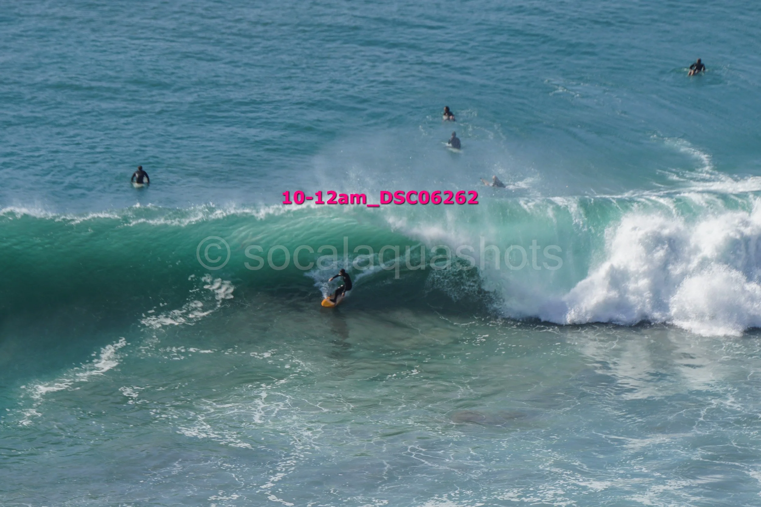 Surfer riding a wave with multiple surfers in the background in the ocean