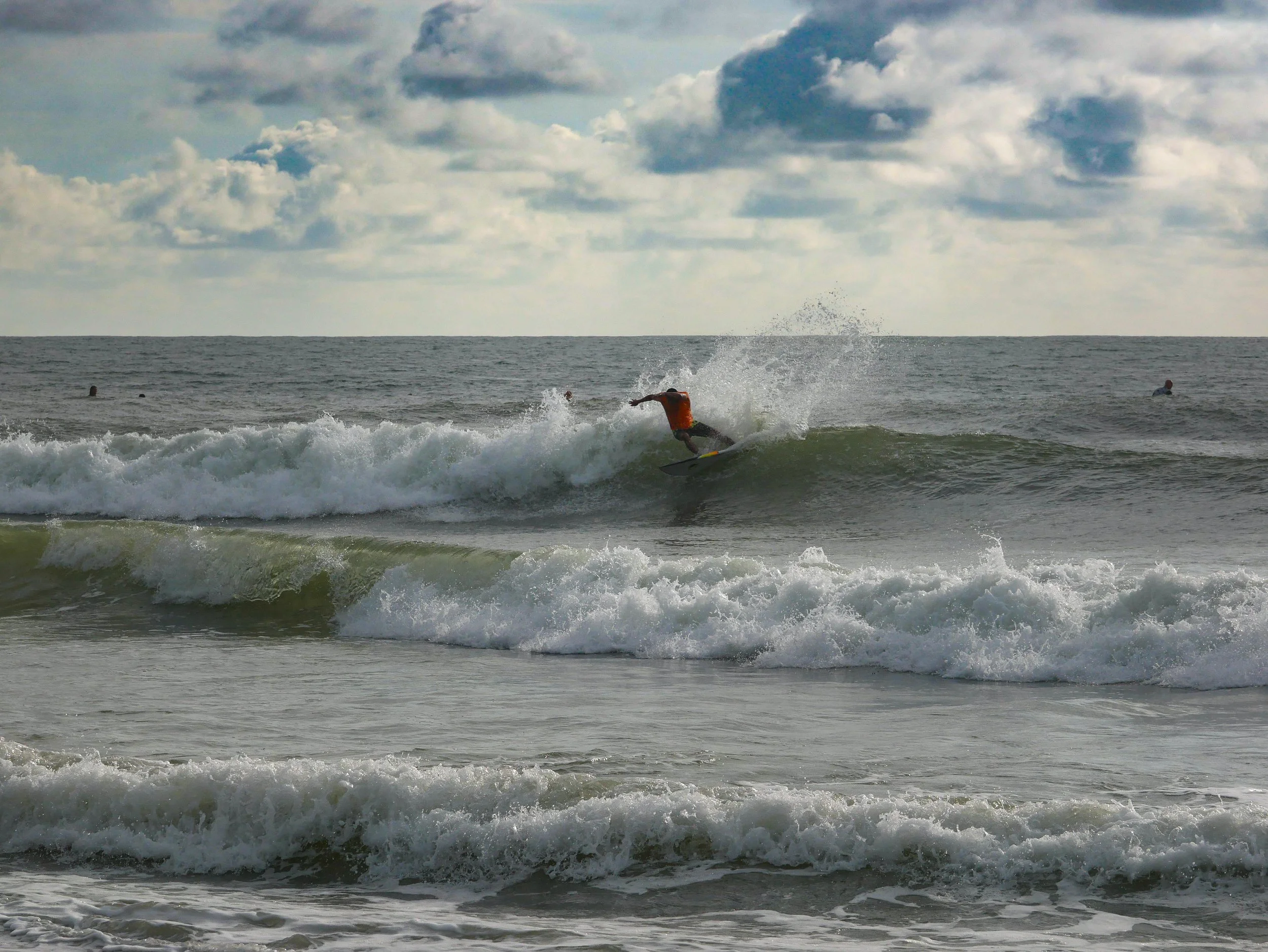Surfer riding a wave in cloudy weather at sea