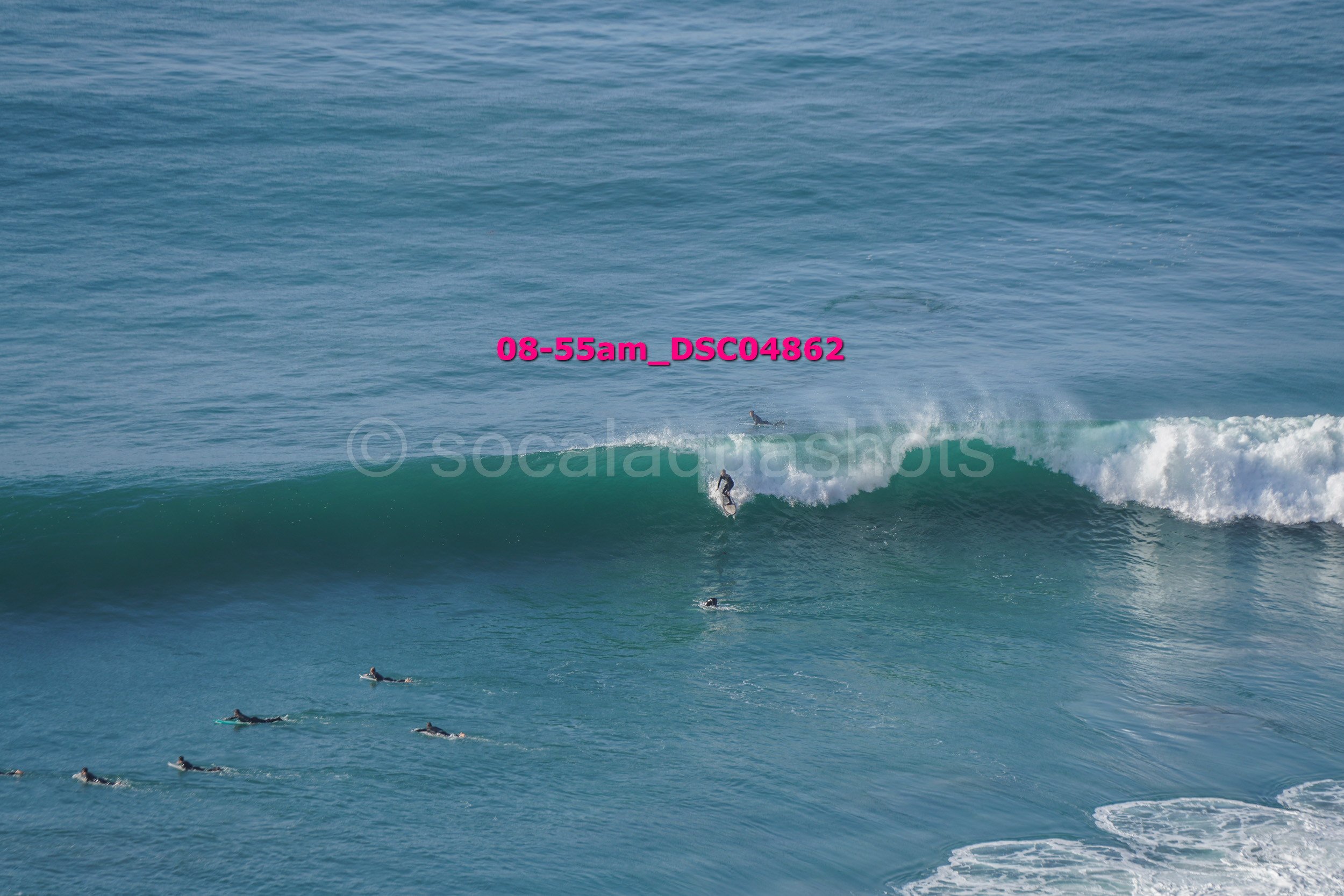 Surfer riding a wave with several other surfers in the water