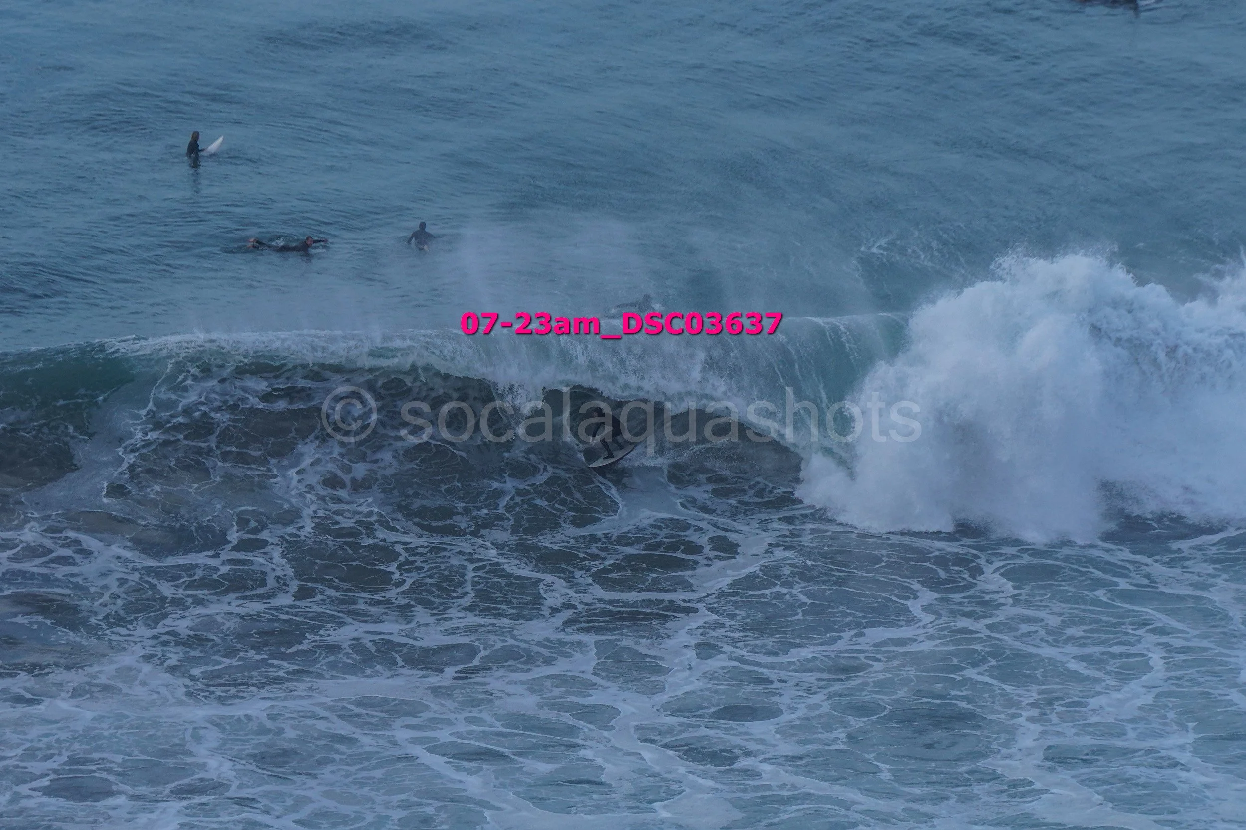 Surfers riding and waiting for waves in the ocean during daytime.