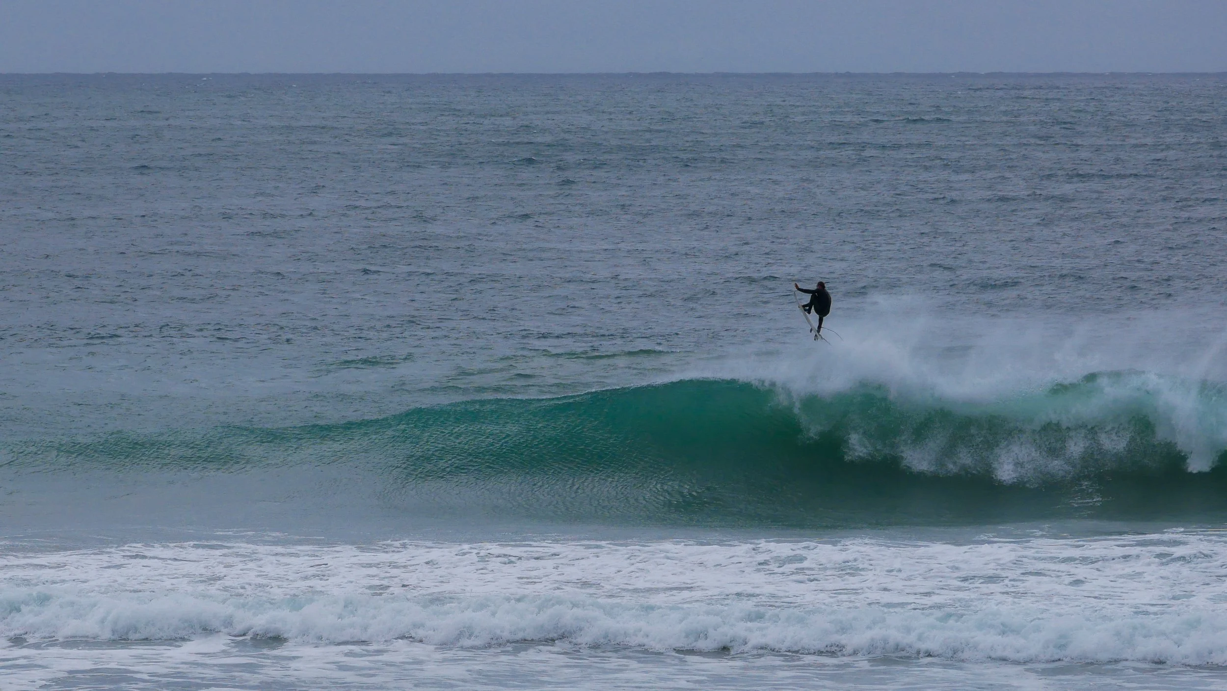 Surfer performing aerial maneuver over a wave in ocean