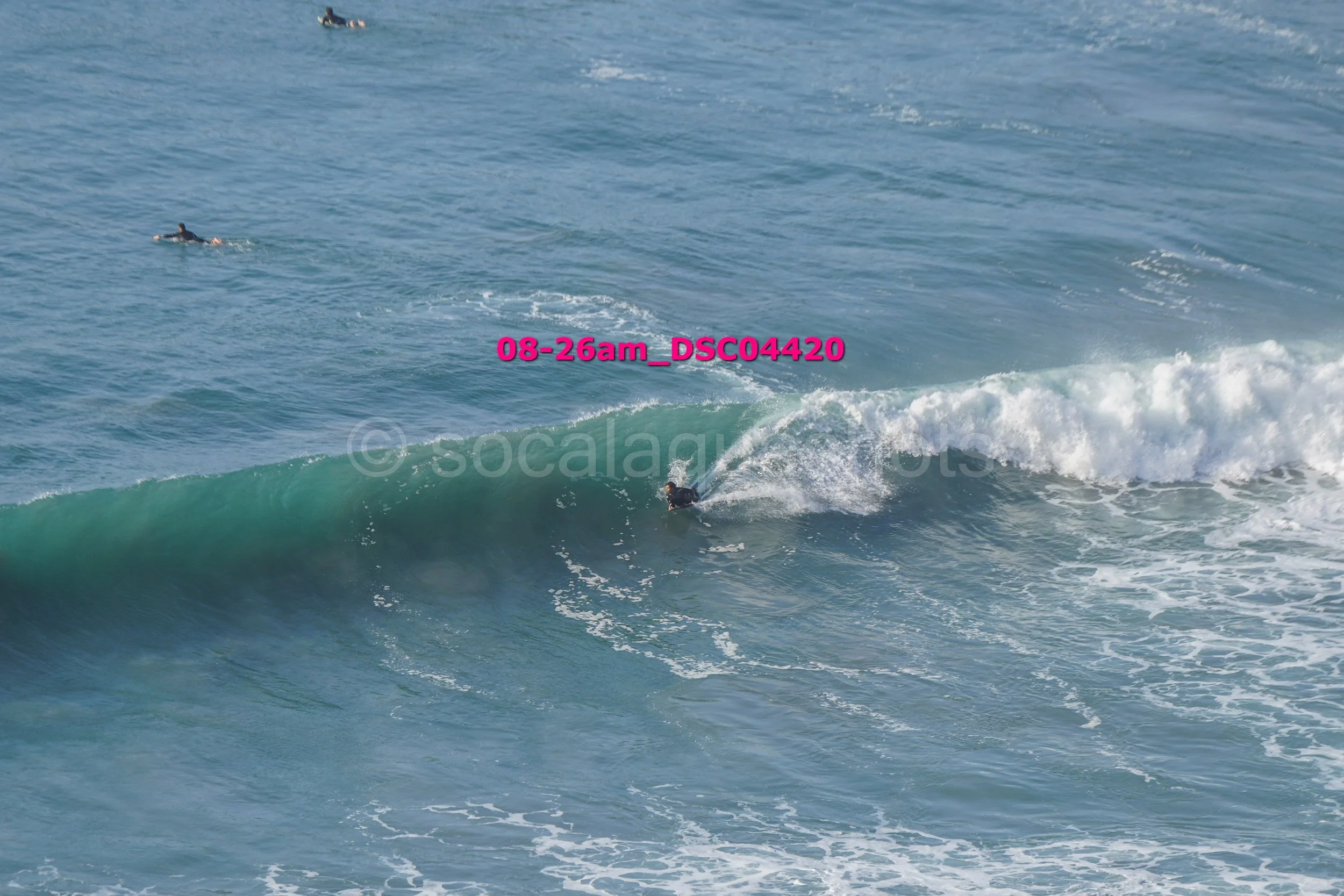 A person surfing on a wave in the ocean with another surfer in the distance.