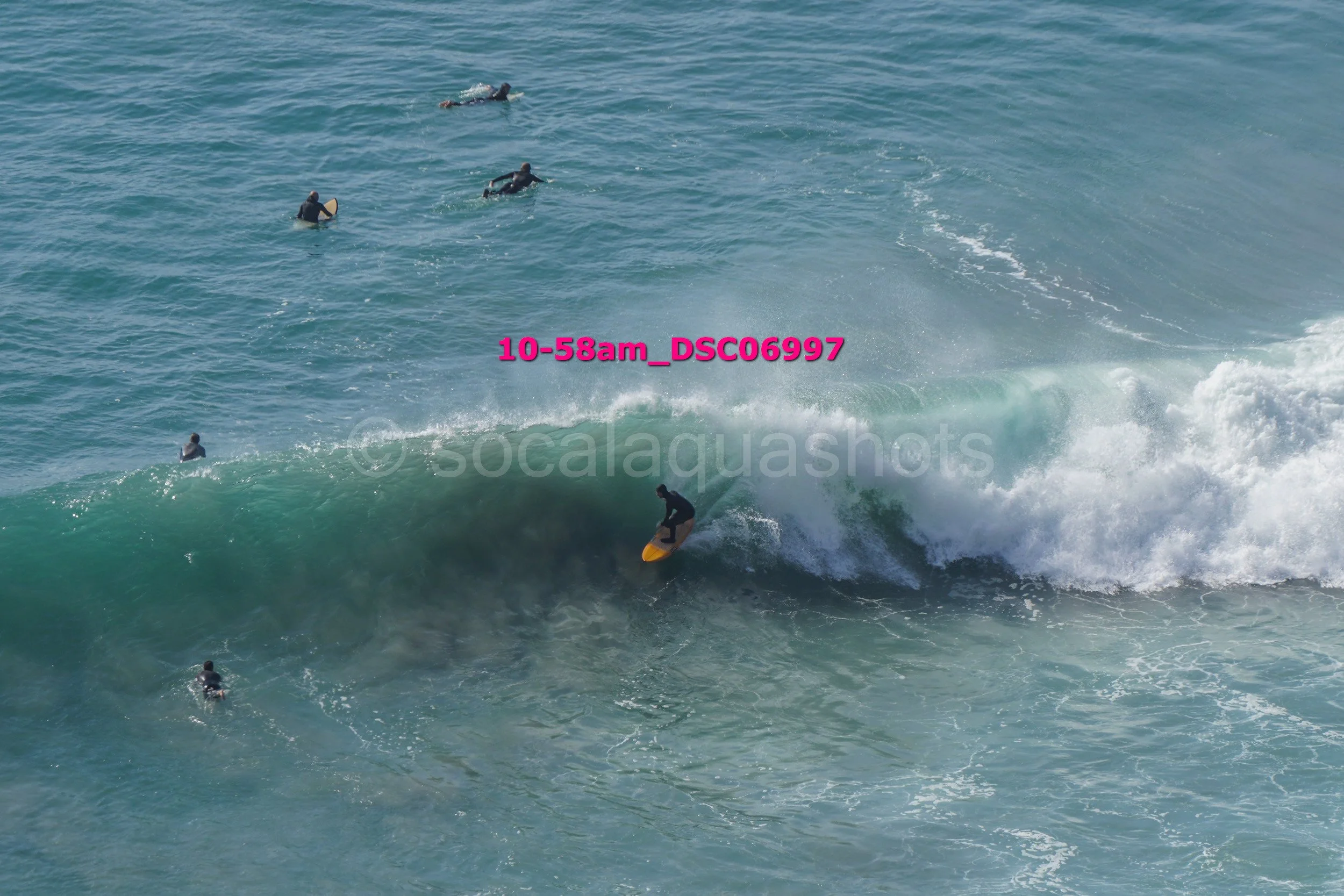 Surfer riding a wave with several surfers in the water nearby in the ocean.