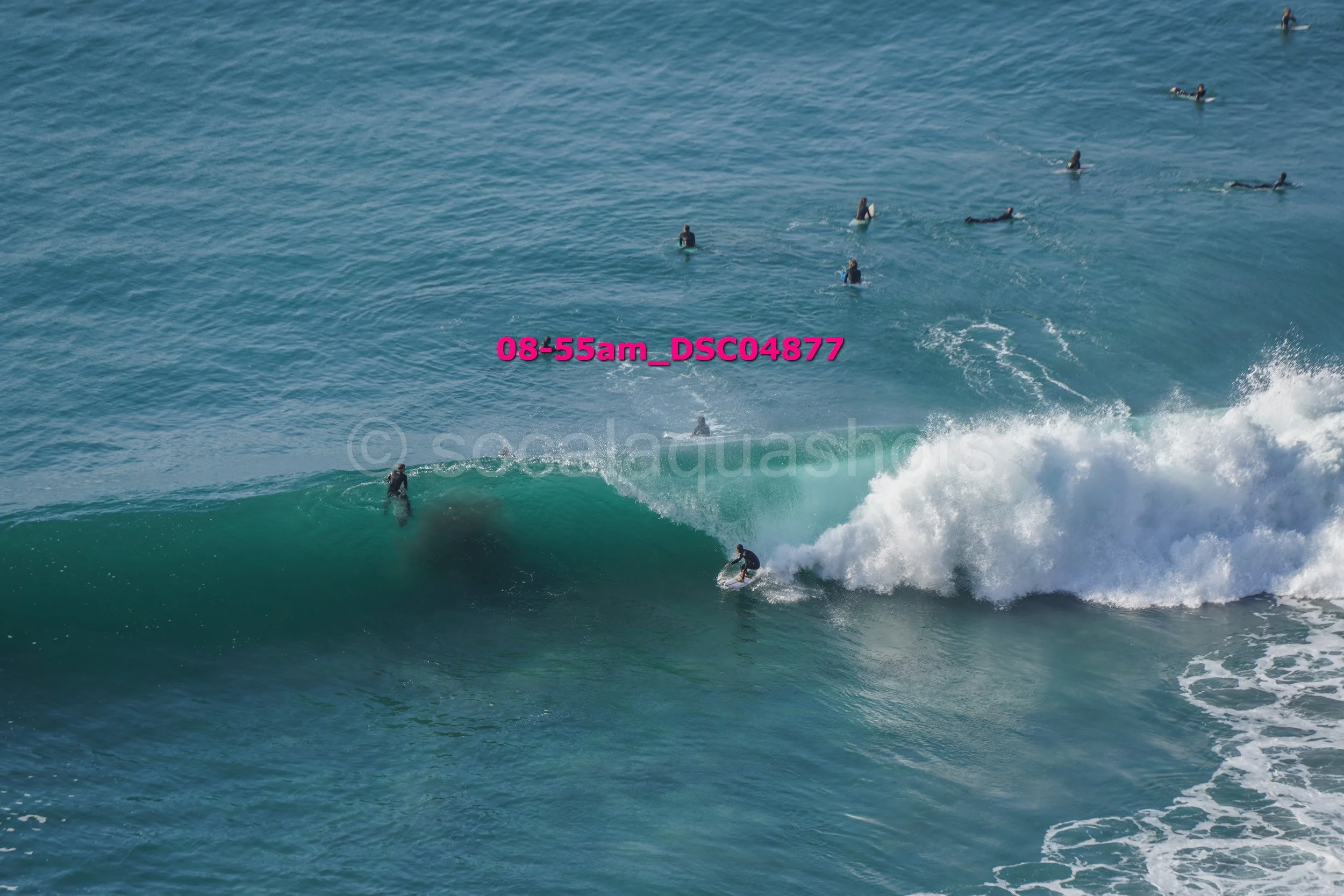 Surfer riding a wave with several surfers in the water nearby.