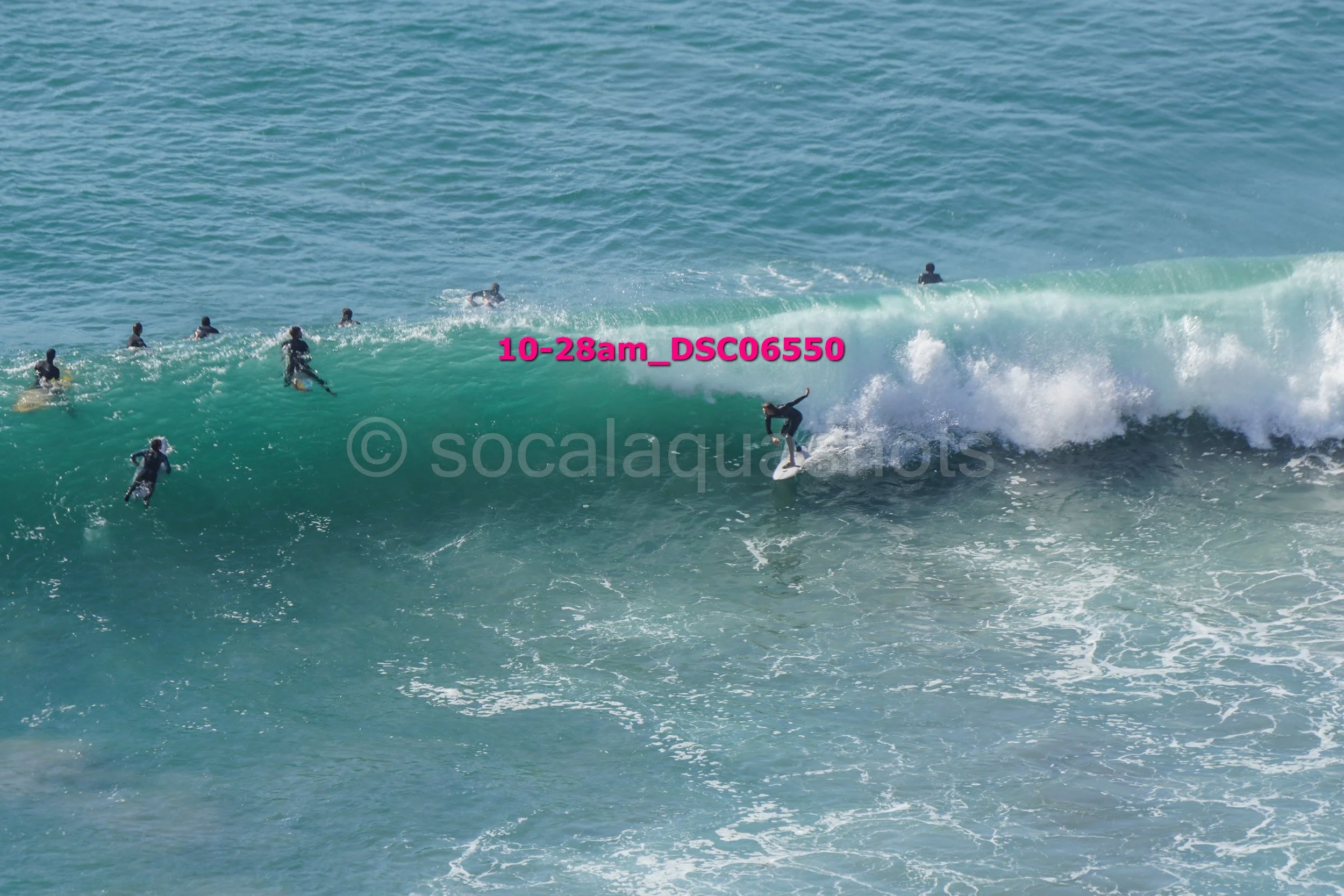 Surfer riding a large wave with multiple surfers in the water nearby