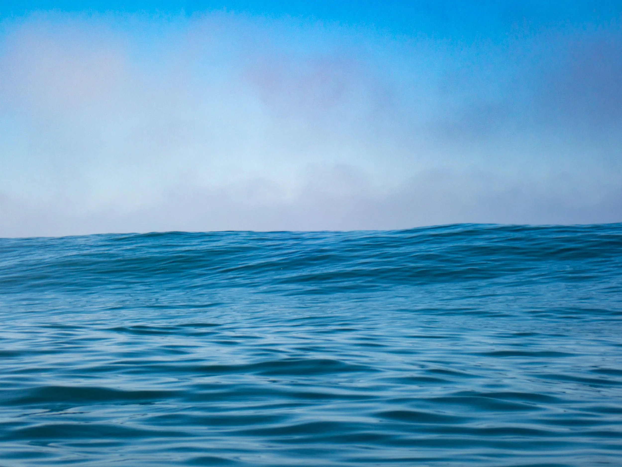 Ocean with gentle waves and a cloudy sky in the background.
